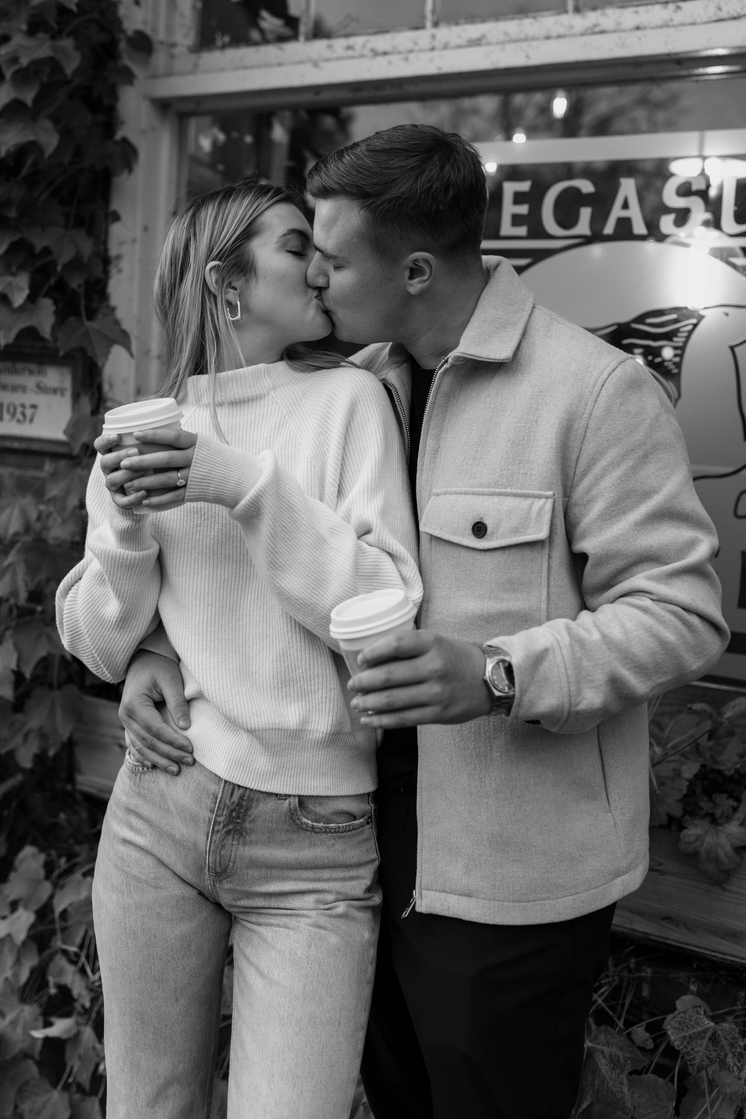 Couple kissing outdoors while holding coffee cups