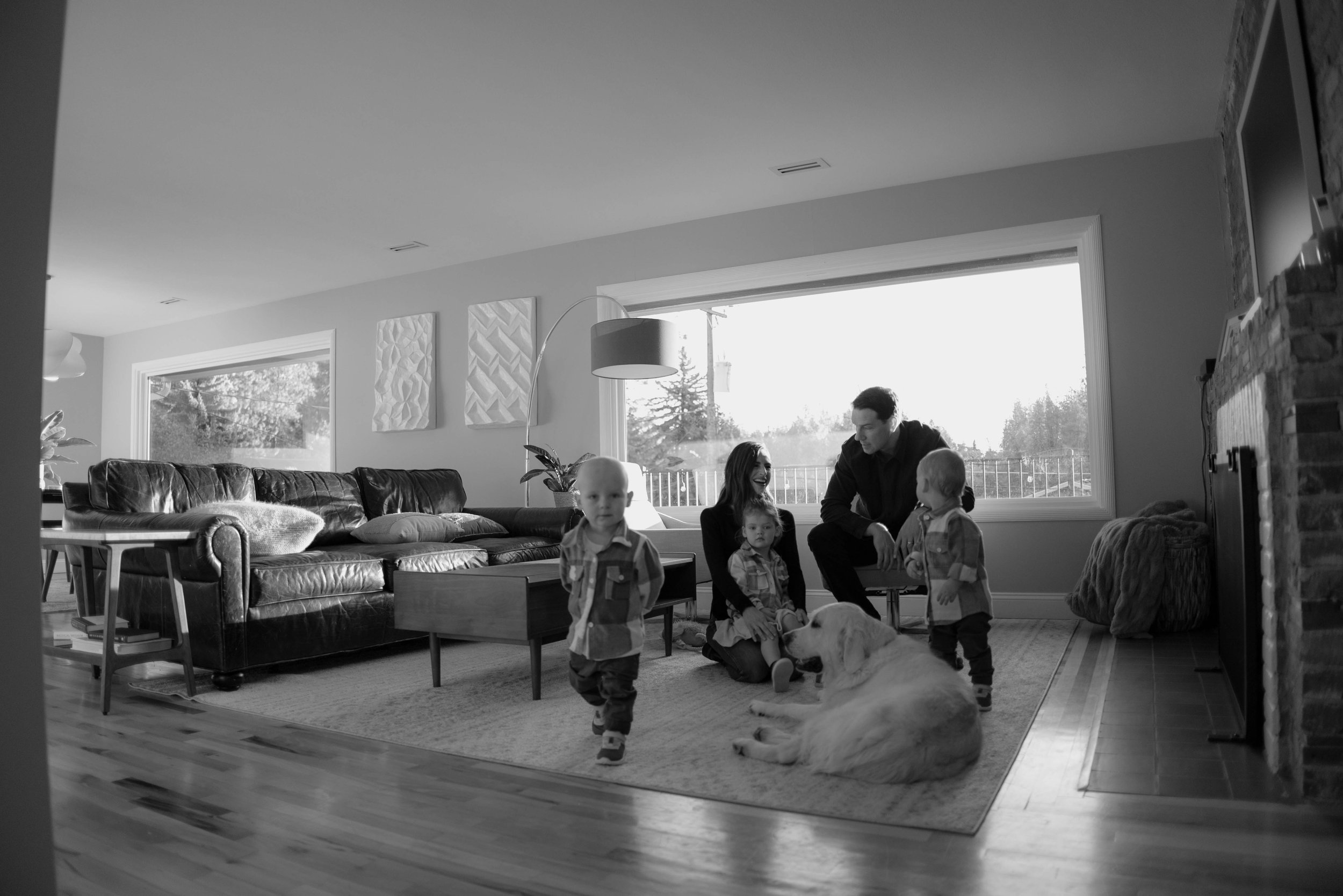 Family in living room with toddlers and dog, black and white photo