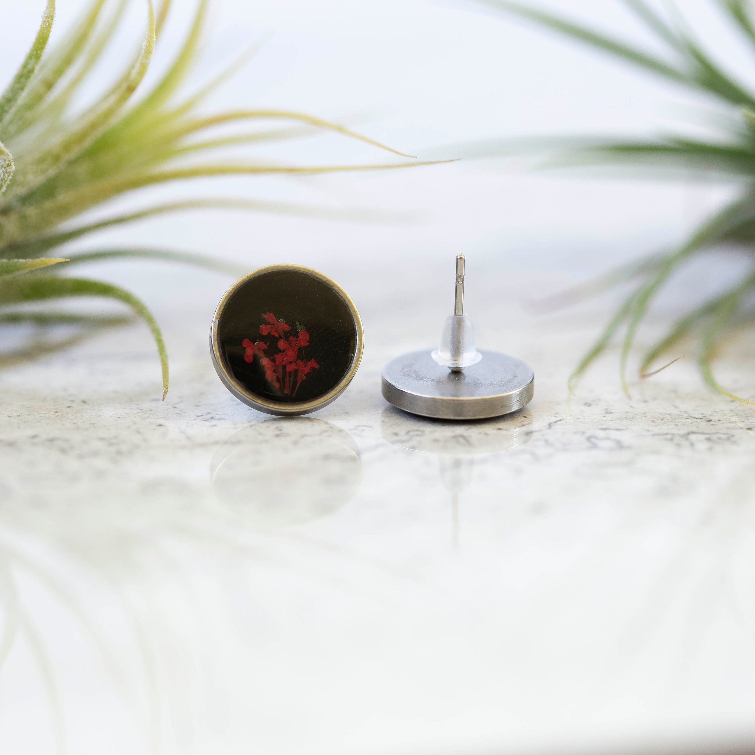 These unique one of a kind botanical earrings have tiny little red flowers on a black background and a stainless steel base.