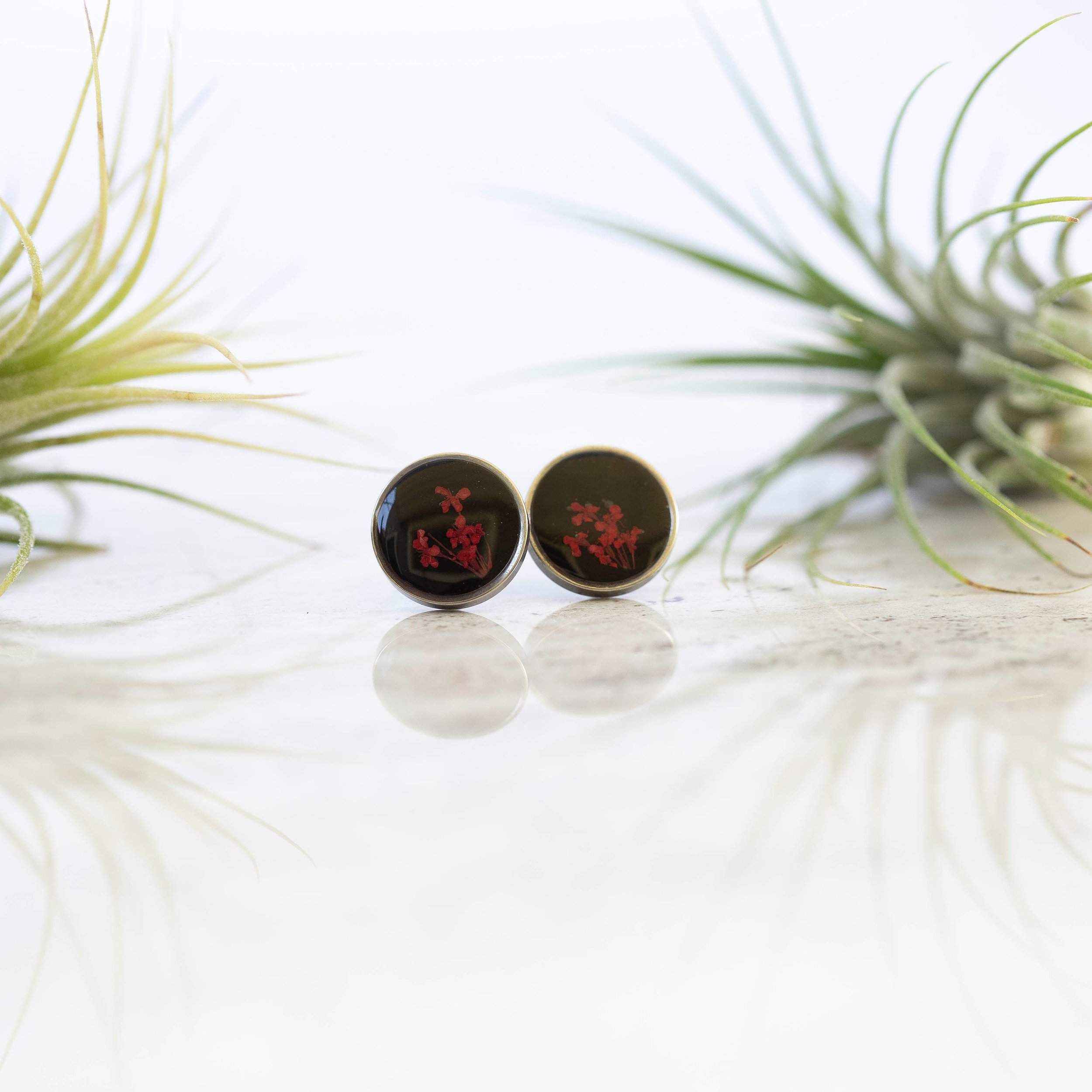 These unique one of a kind botanical earrings have tiny little red flowers on a black background and a stainless steel base.
