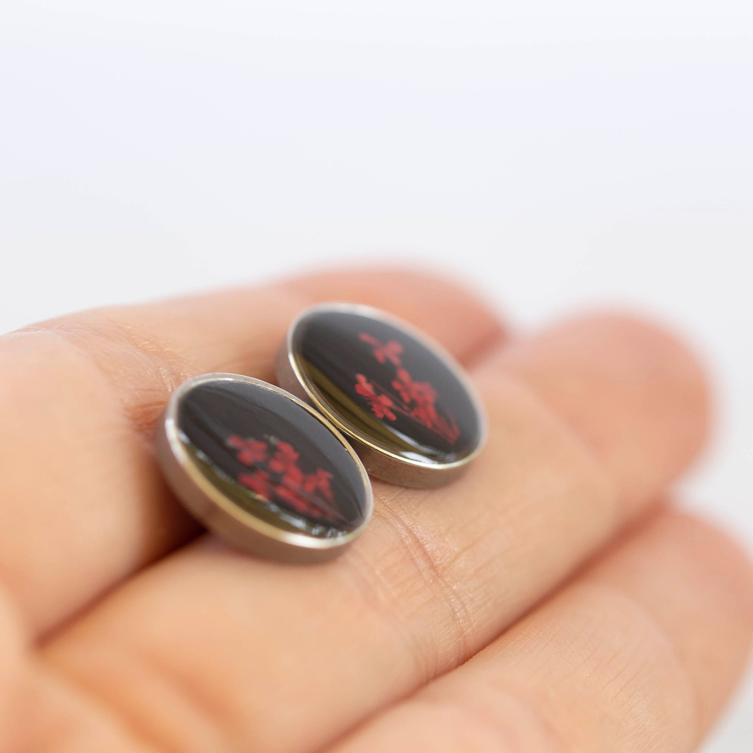 These unique one of a kind botanical earrings have tiny little red flowers on a black background and a stainless steel base.
