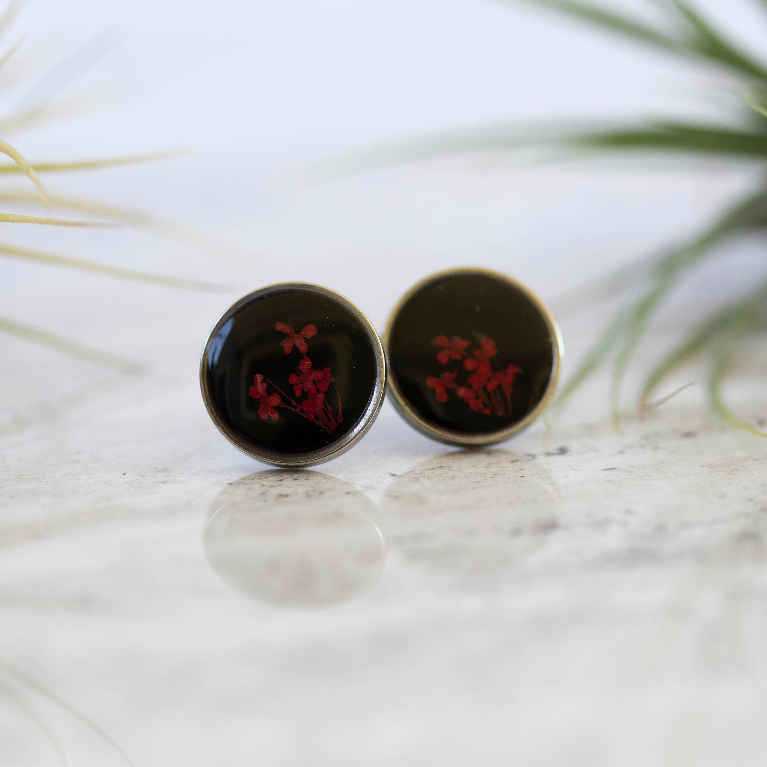 These unique one of a kind botanical earrings have tiny little red flowers on a black background and a stainless steel base.