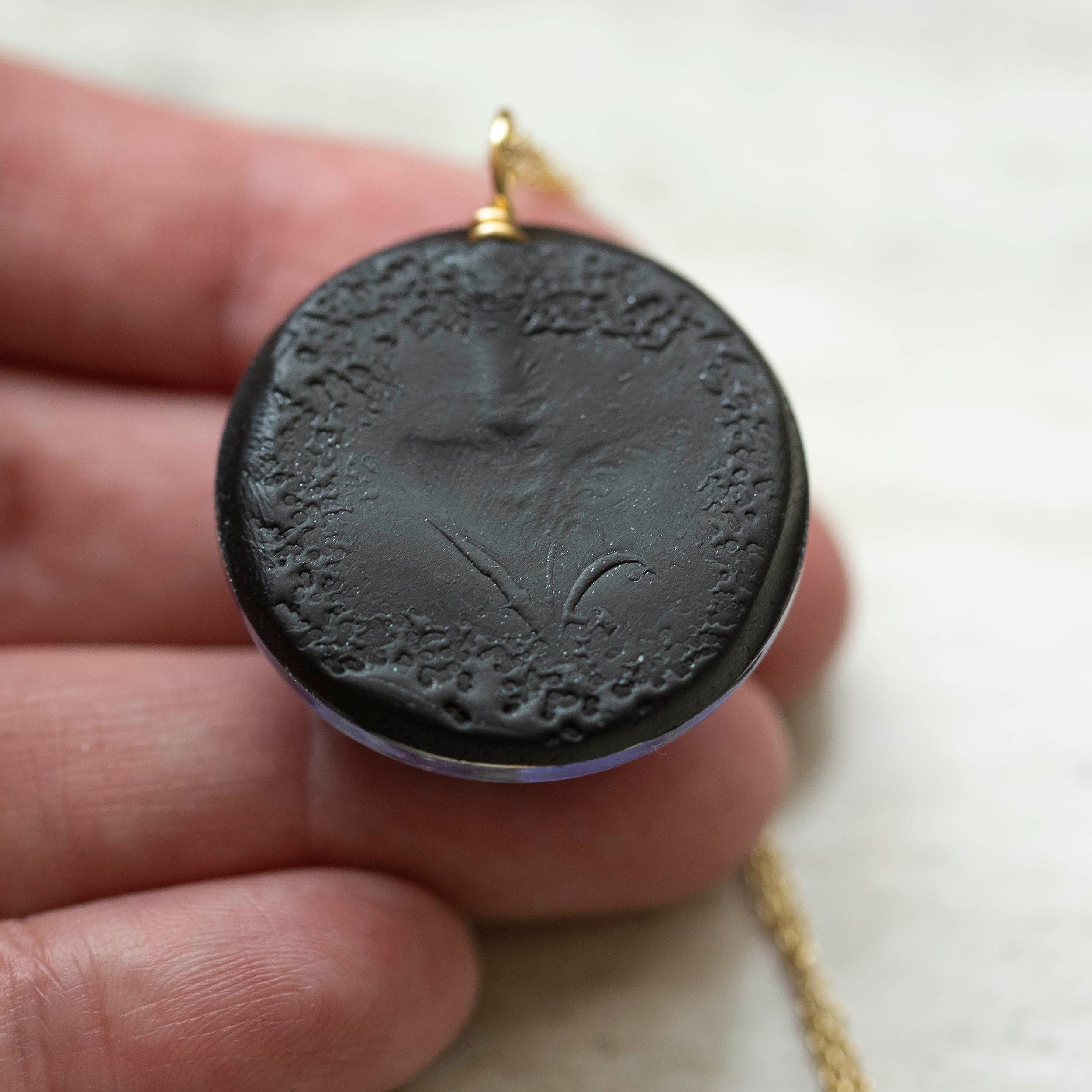 Beautiful real Purple Flower In a resin dome with a black clay back on a gold chain.
