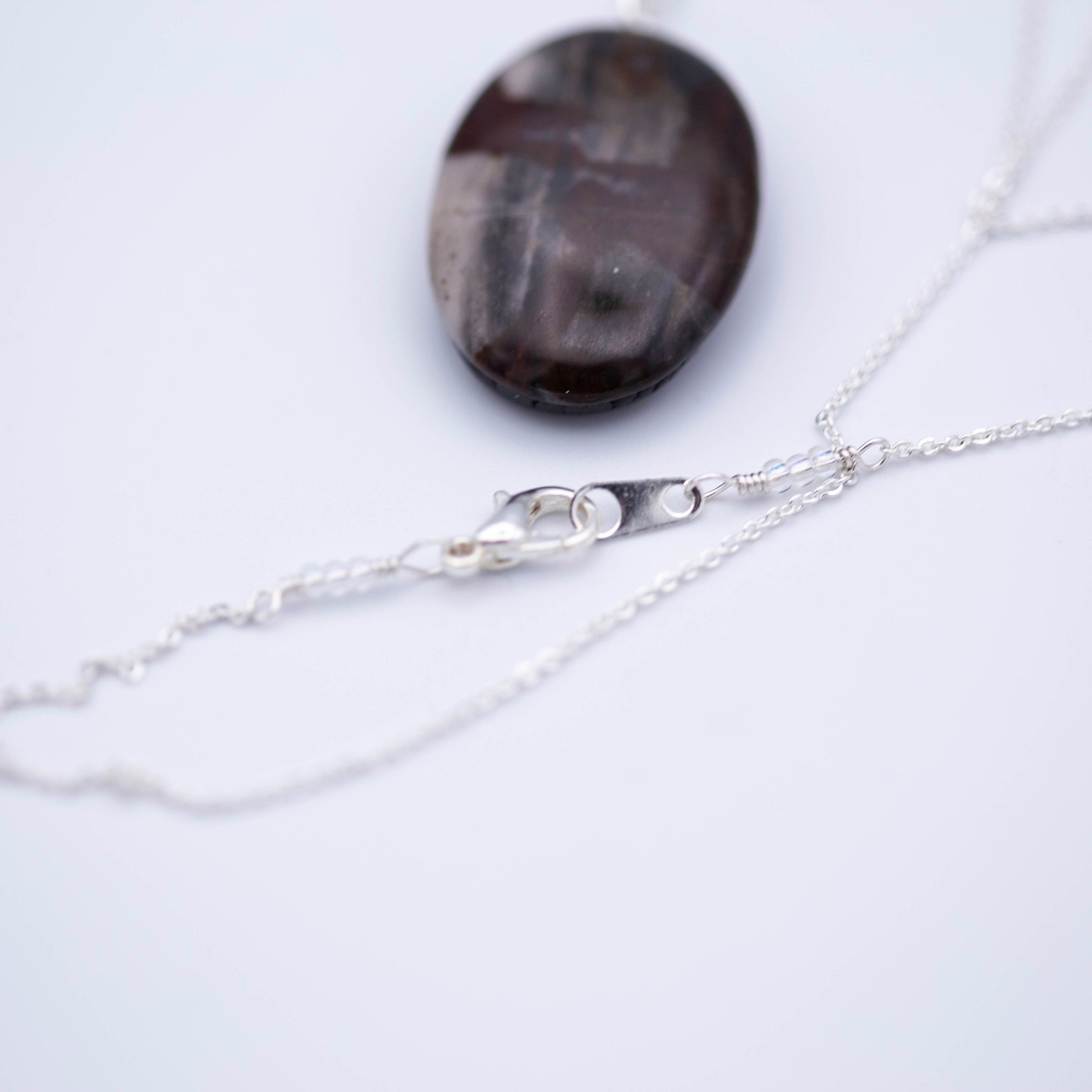 Australian outback jasper stone that has earthy brown and beige colors with black clay on the back silver gemstone necklace.