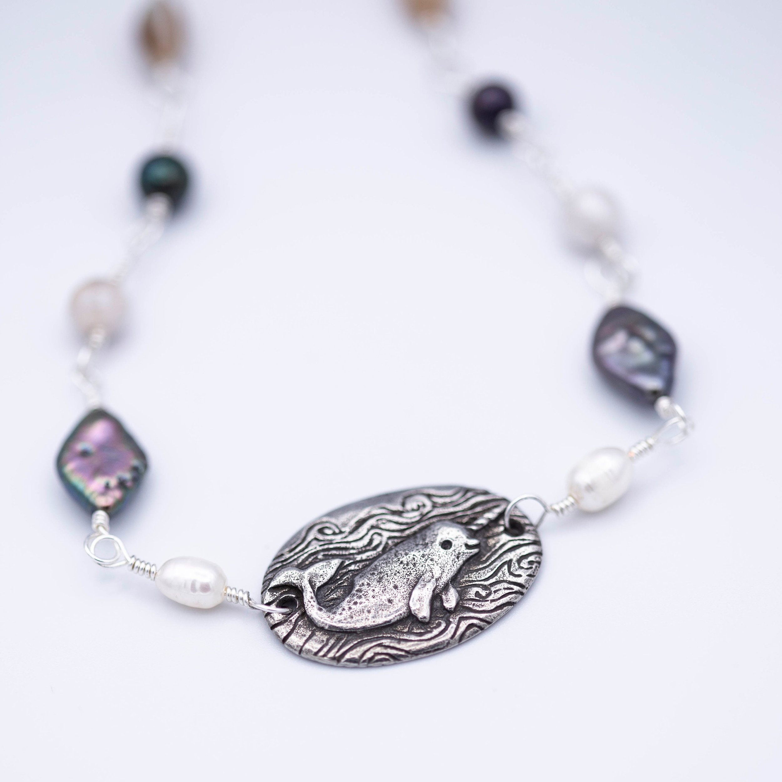 Sweet little narwhal pewter pendant with Magic is everywhere written on the back on a hand wrapped chain made of pearl and shell beads.