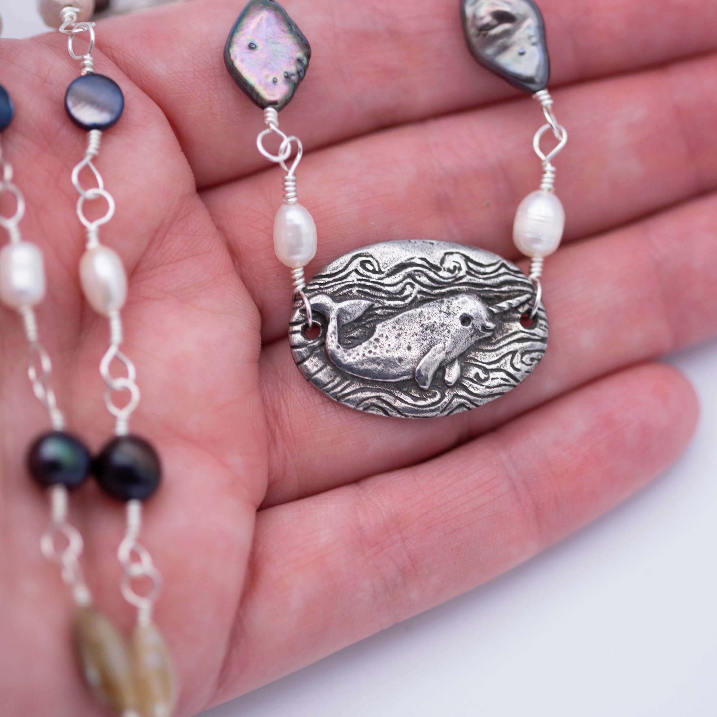 Sweet little narwhal pewter pendant with Magic is everywhere written on the back on a hand wrapped chain made of pearl and shell beads.