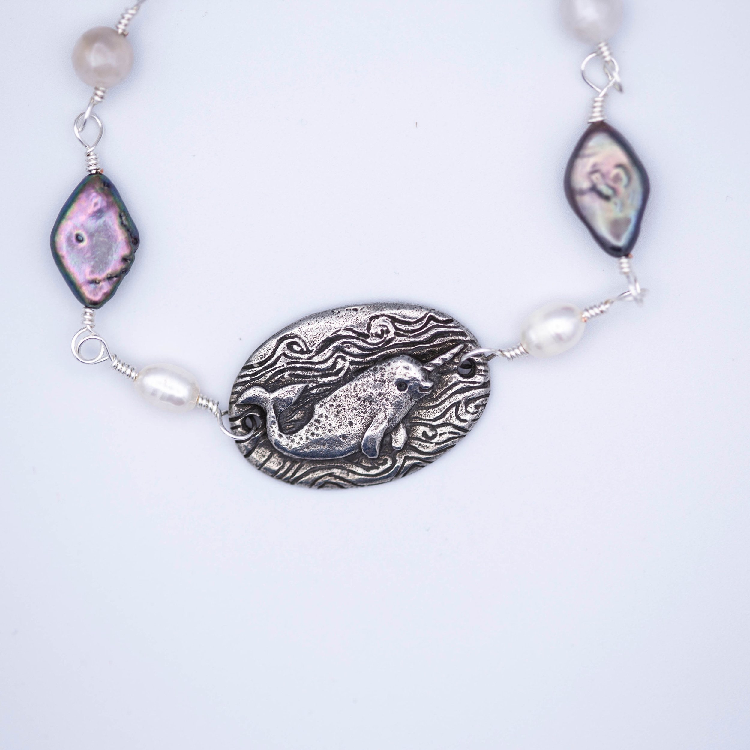 Sweet little narwhal pewter pendant with Magic is everywhere written on the back on a hand wrapped chain made of pearl and shell beads.