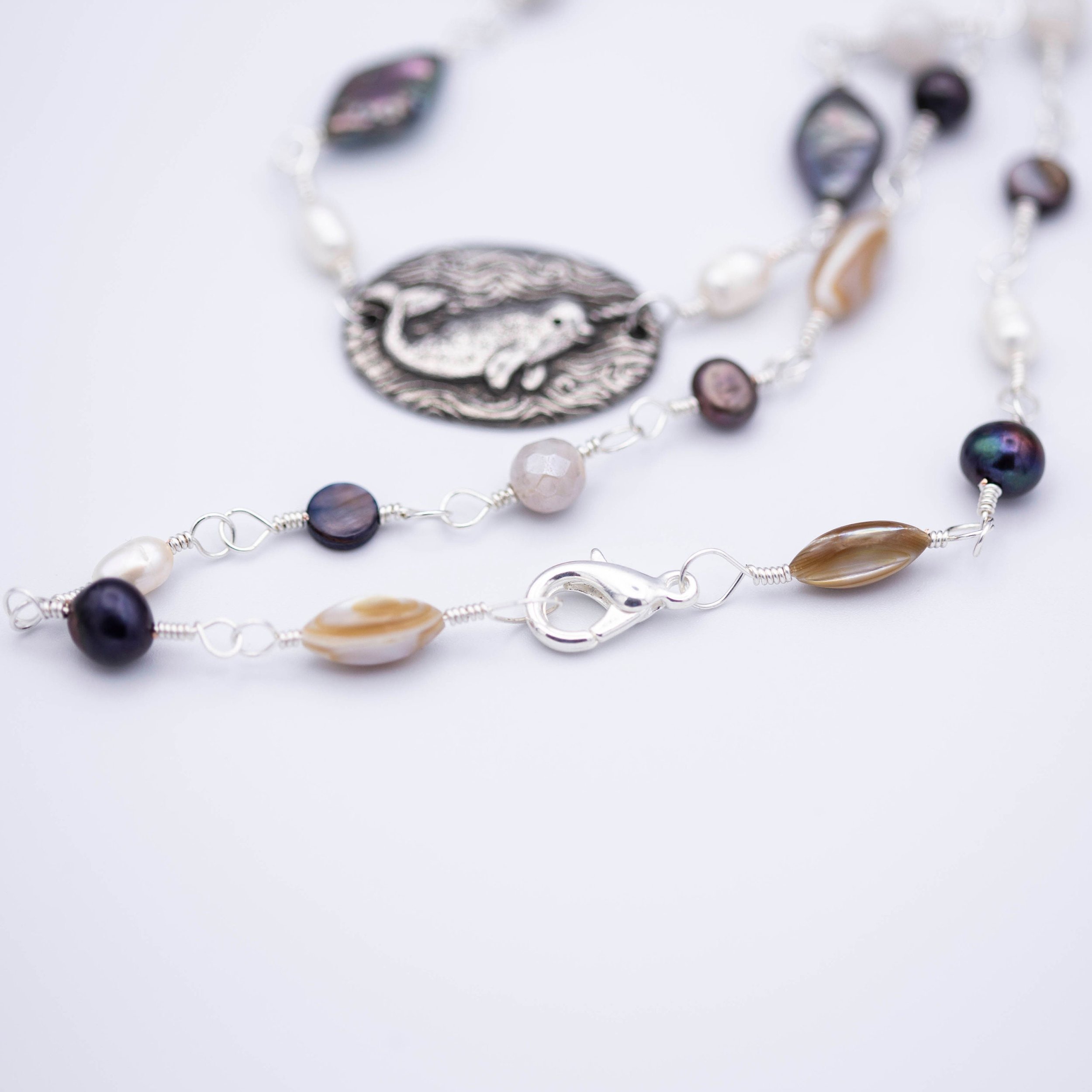 Sweet little narwhal pewter pendant with Magic is everywhere written on the back on a hand wrapped chain made of pearl and shell beads.