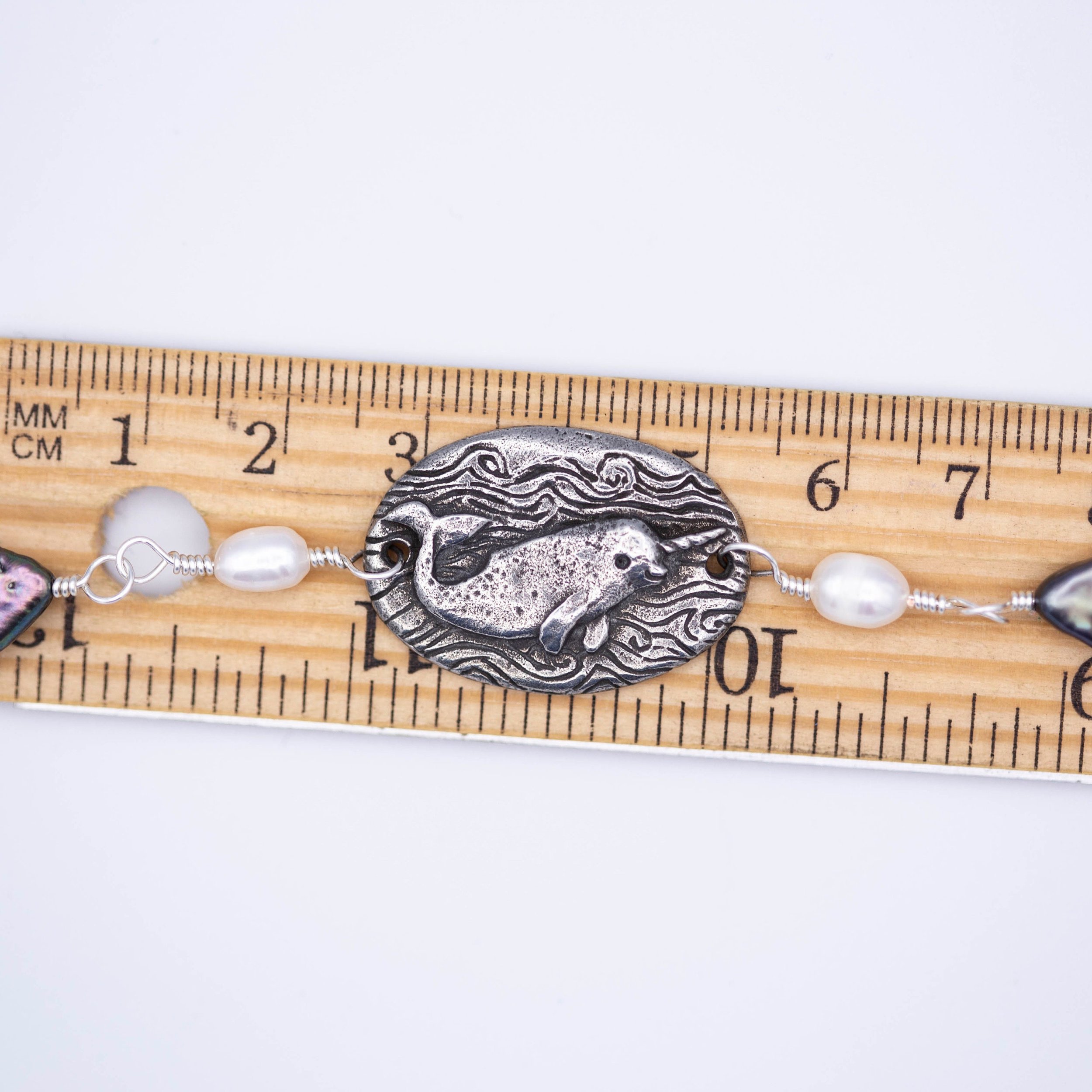 Sweet little narwhal pewter pendant with Magic is everywhere written on the back on a hand wrapped chain made of pearl and shell beads.