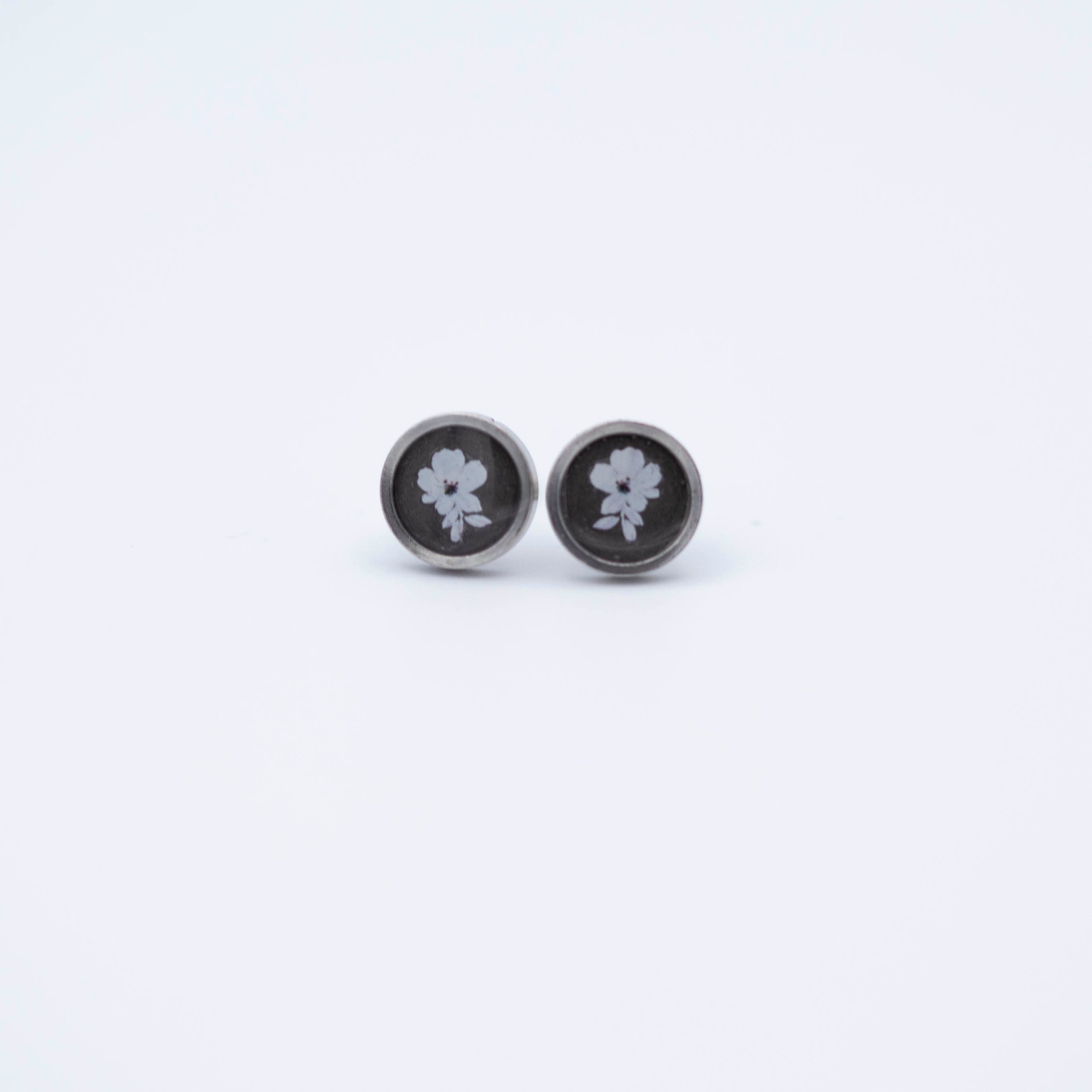 Tiny white flower design with white bronze metallic background stainless steel earrings.