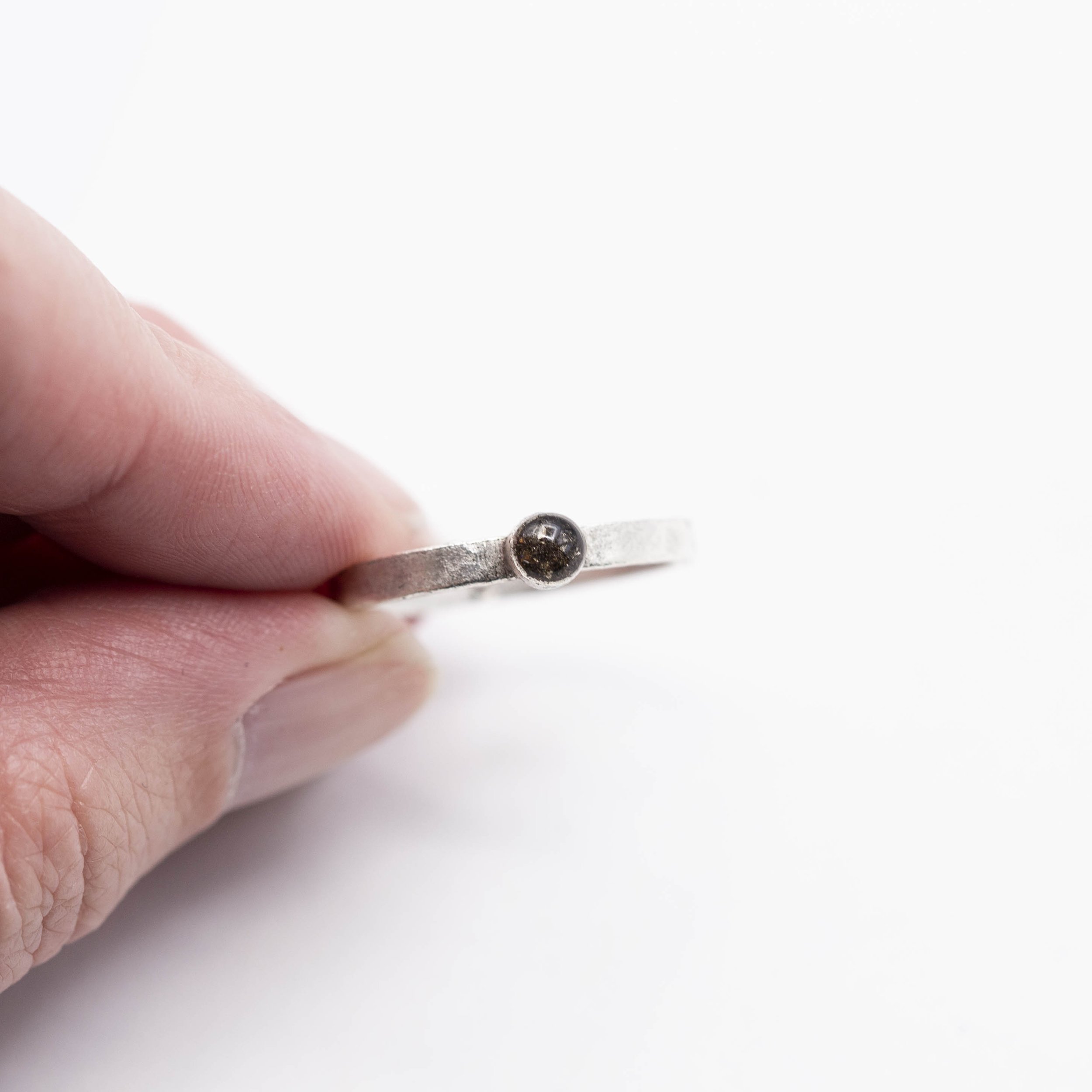 A fine silver plated pewter stacking ring with a bold circle setting of Canyon Diablo Meteorite in resin, bringing the stars closer to you.