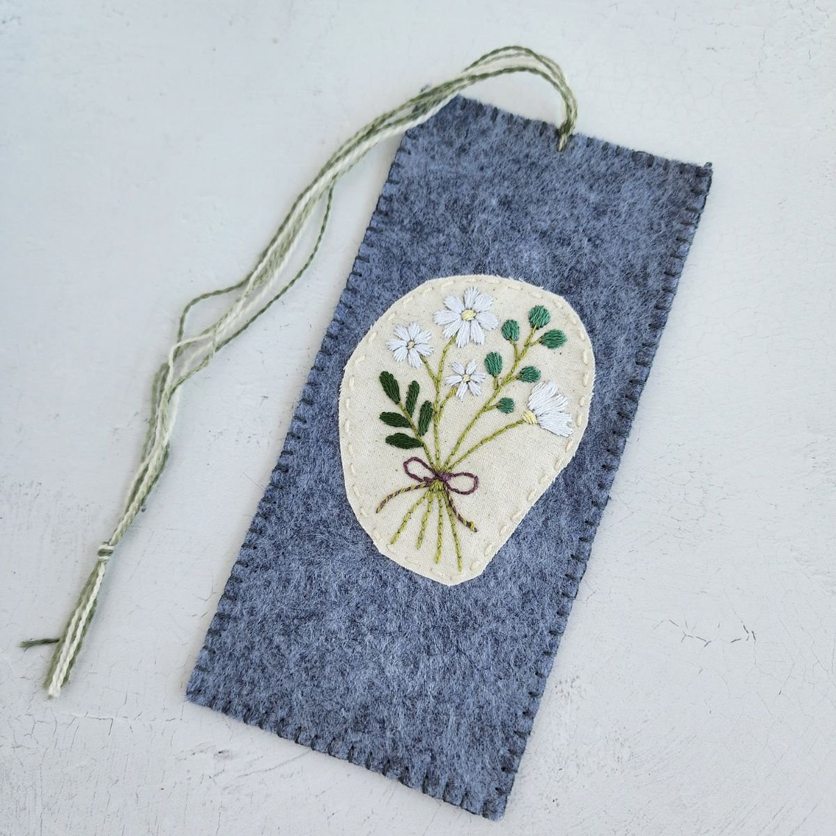 Hand embroidered white floral bookmark made from wool blend felt, finished with a naturally dyed wool thread tail.