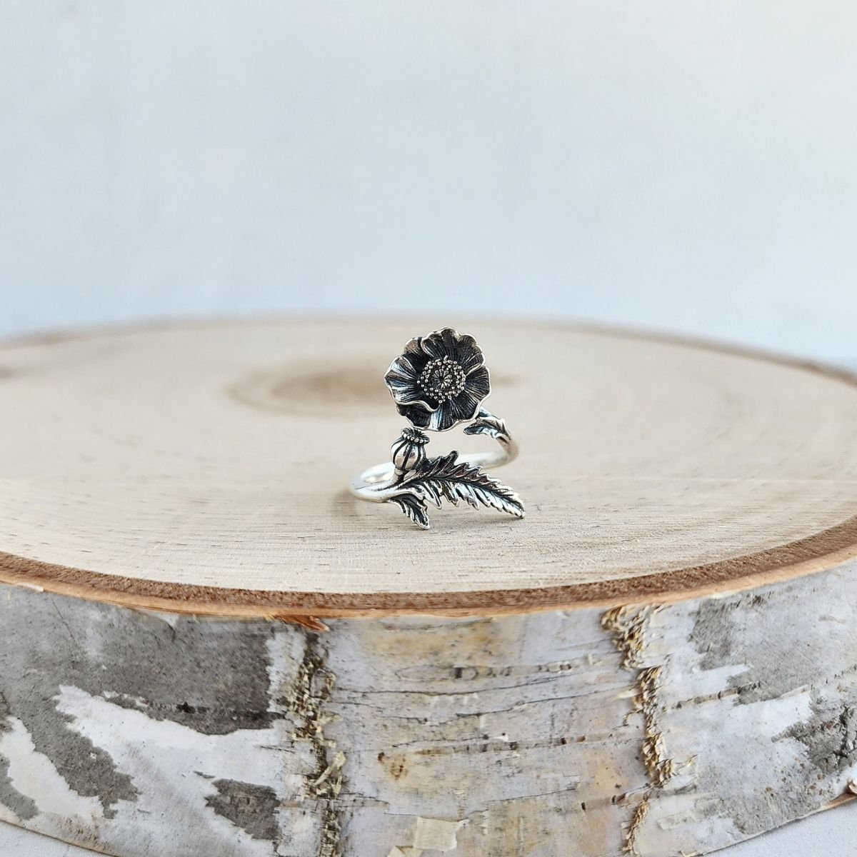 Sterling silver adjustable ring featuring a blooming poppy flower, symbolizing remembrance, healing, and the August birth flower.