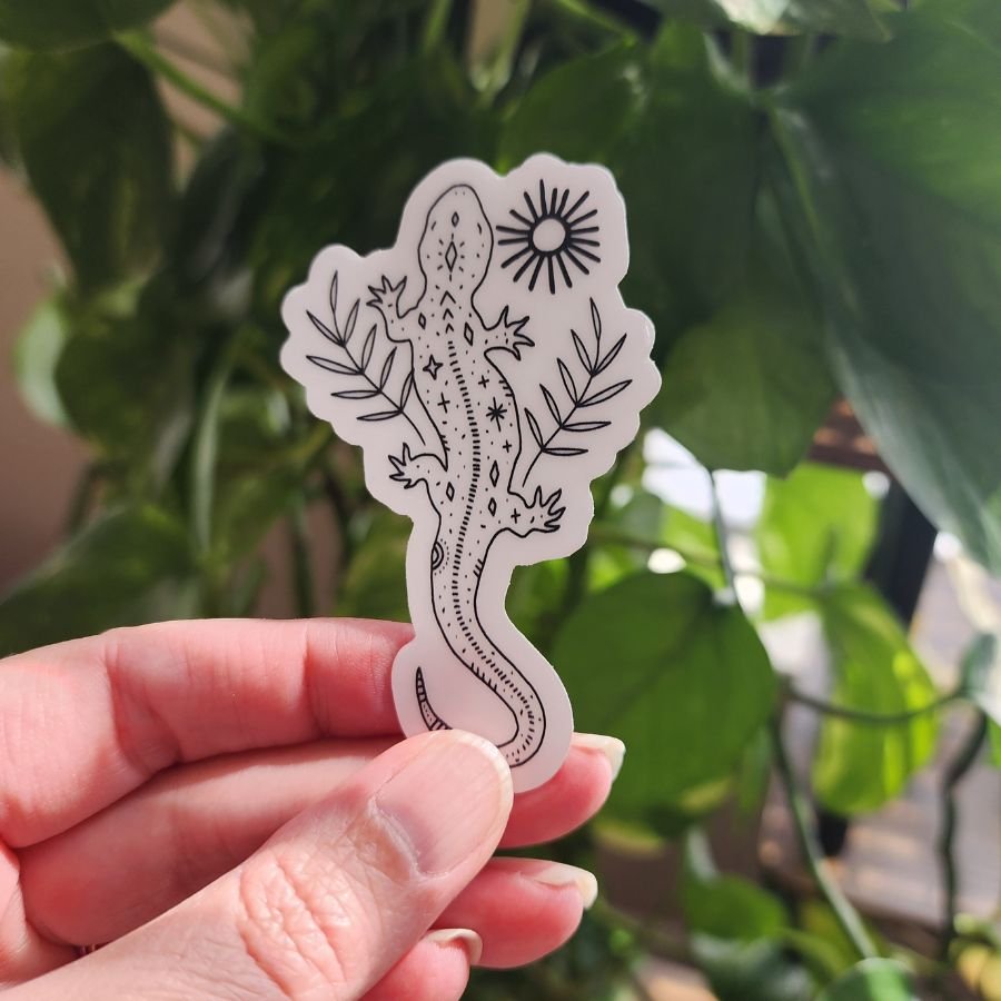 whimsical gecko clear vinyl sticker with sun and botanical leaf elements nature inspired earthy and mystical design for water bottles and journals