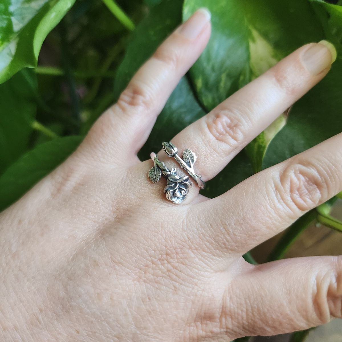 Sterling silver adjustable rose ring with detailed petals, a rosebud, and leafy vine band, representing June’s birth flower.