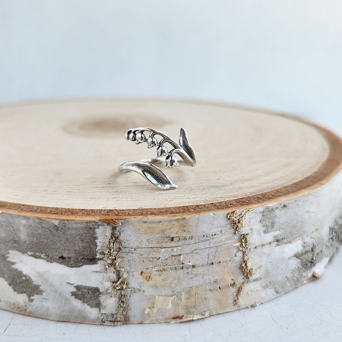 Sterling silver adjustable lily of the valley ring with delicate bell-shaped flowers and leaf-style band, inspired by May’s birth flower.