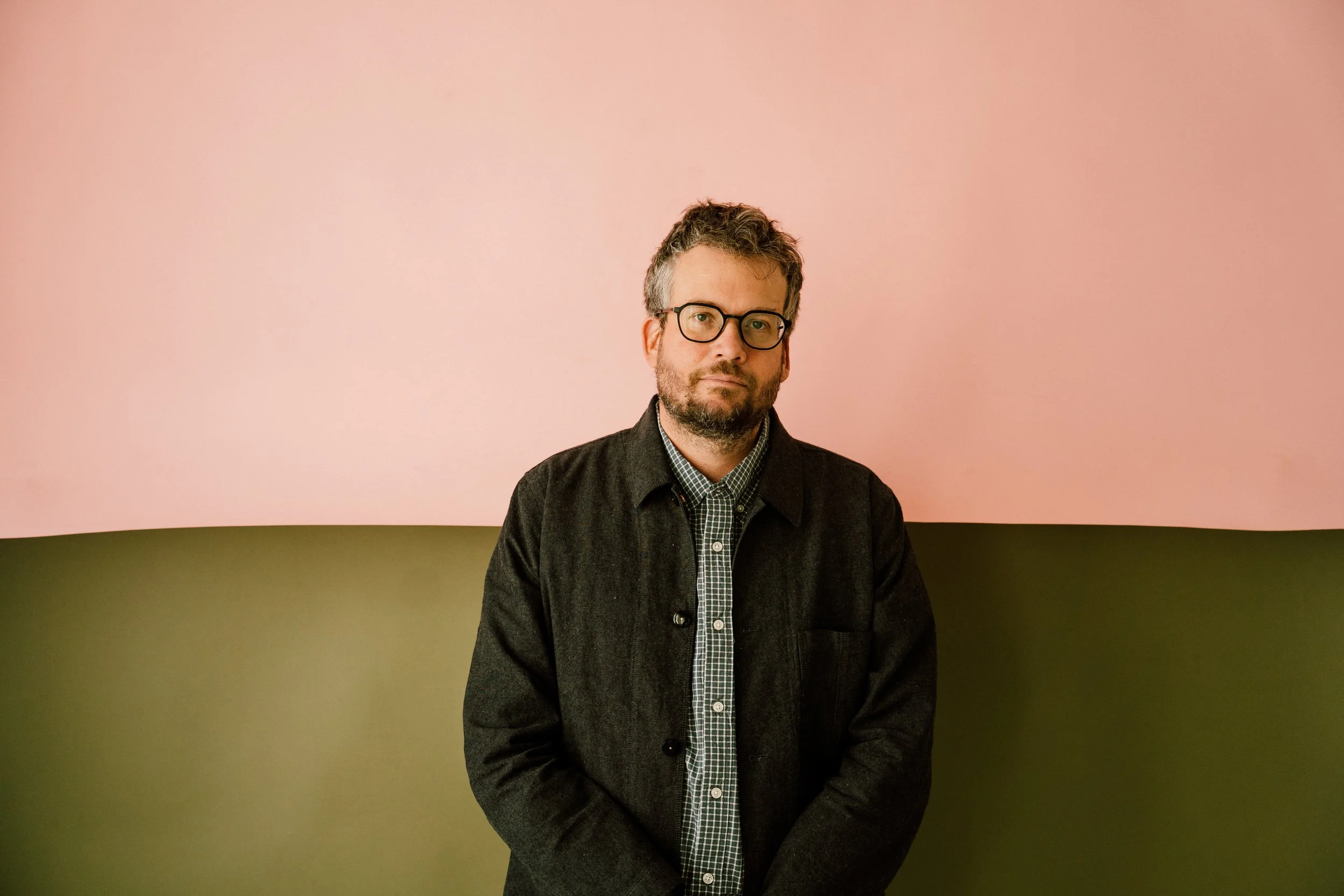 Man (John Green) in front of green and pink backdrop