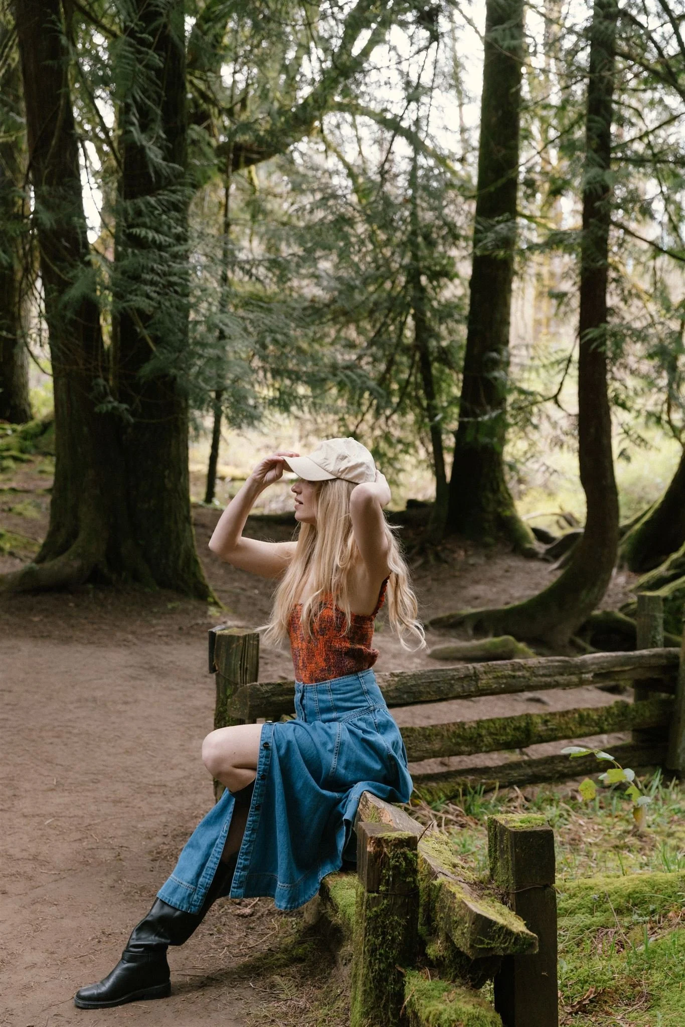 Woman fixing baseball cap among trees