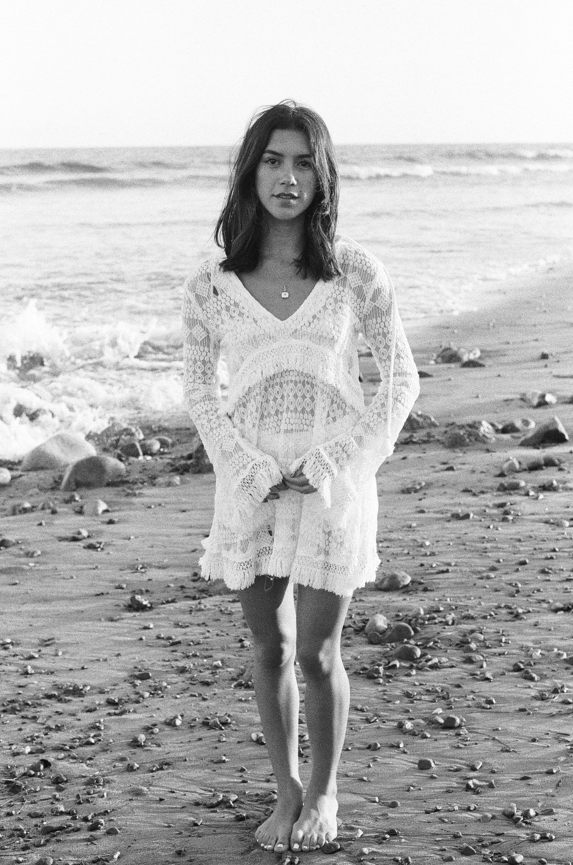 girl stands on beach with waves in the background