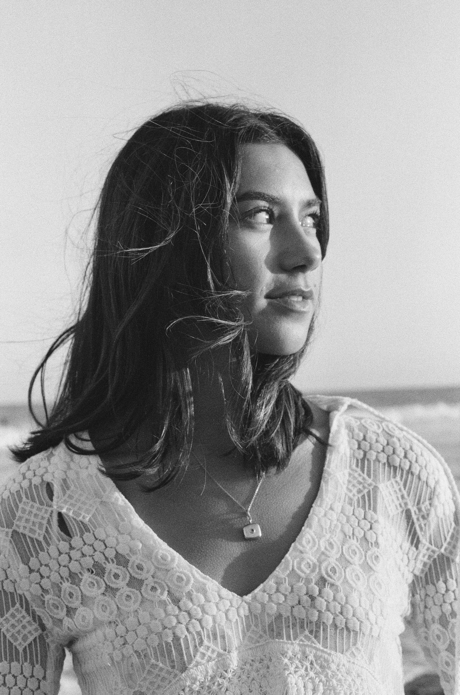 girl stands on beach with waves in the background