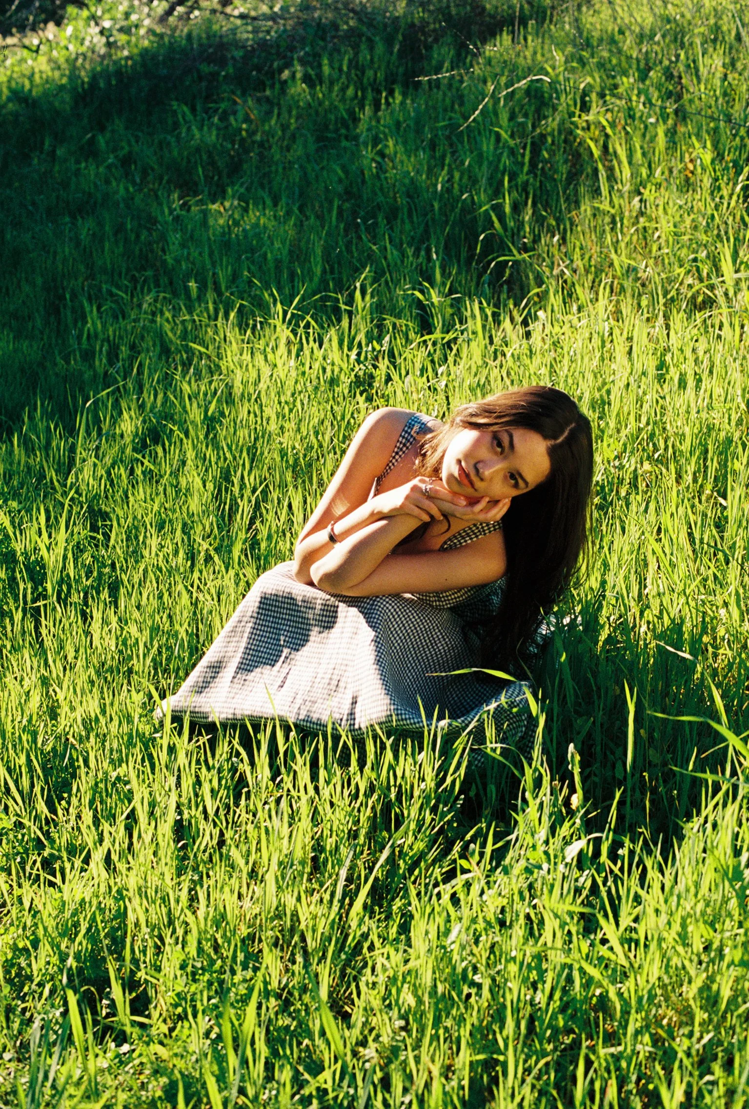 Young woman sits in field of grass