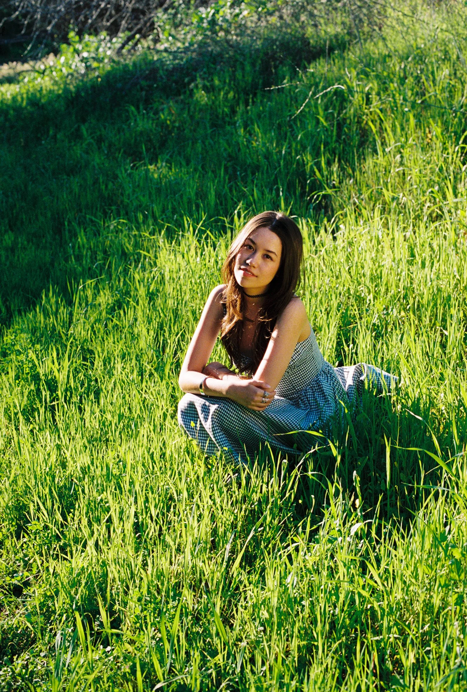 Young woman sits in field of grass