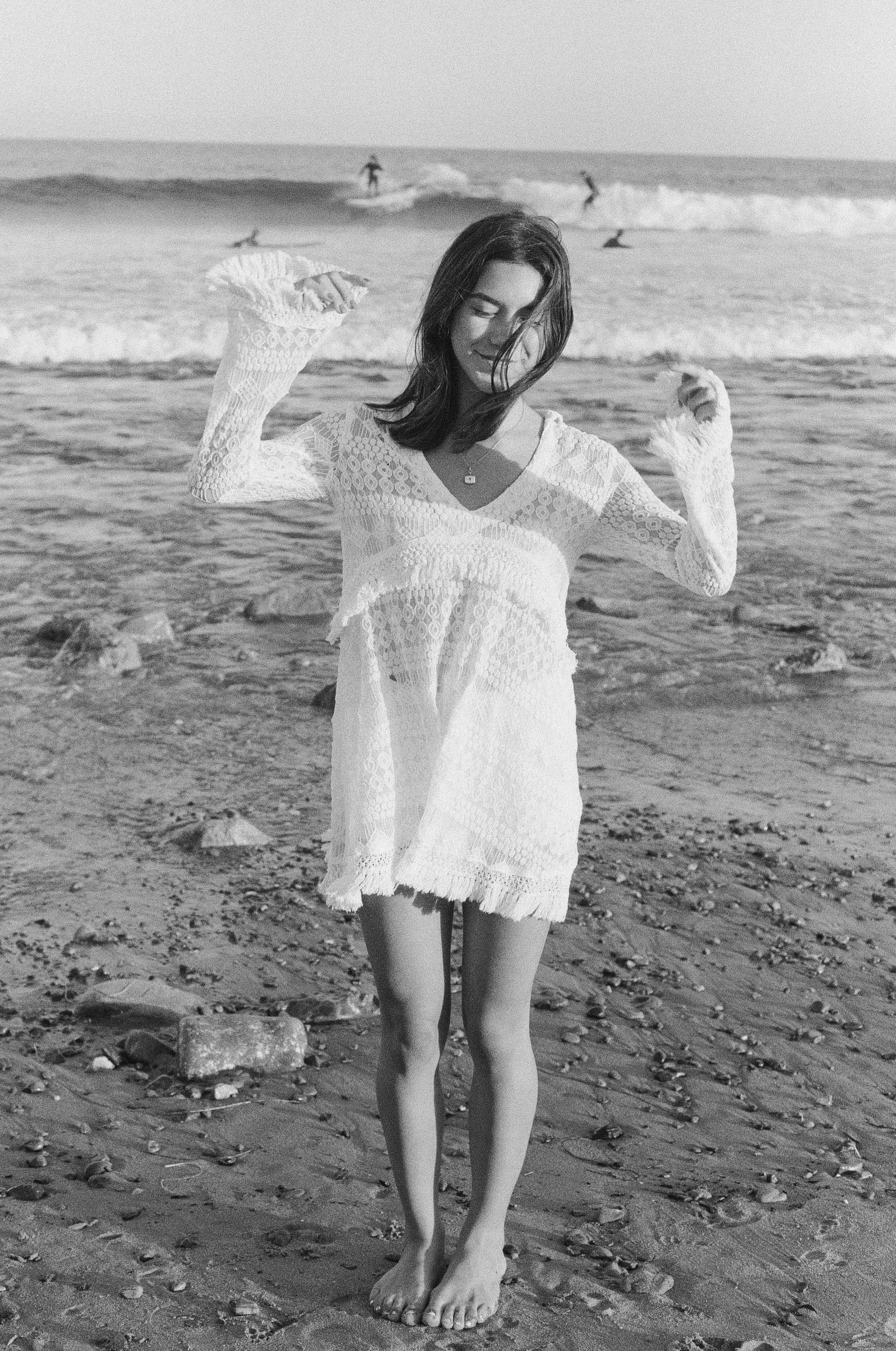 girl stands on beach with waves in the background