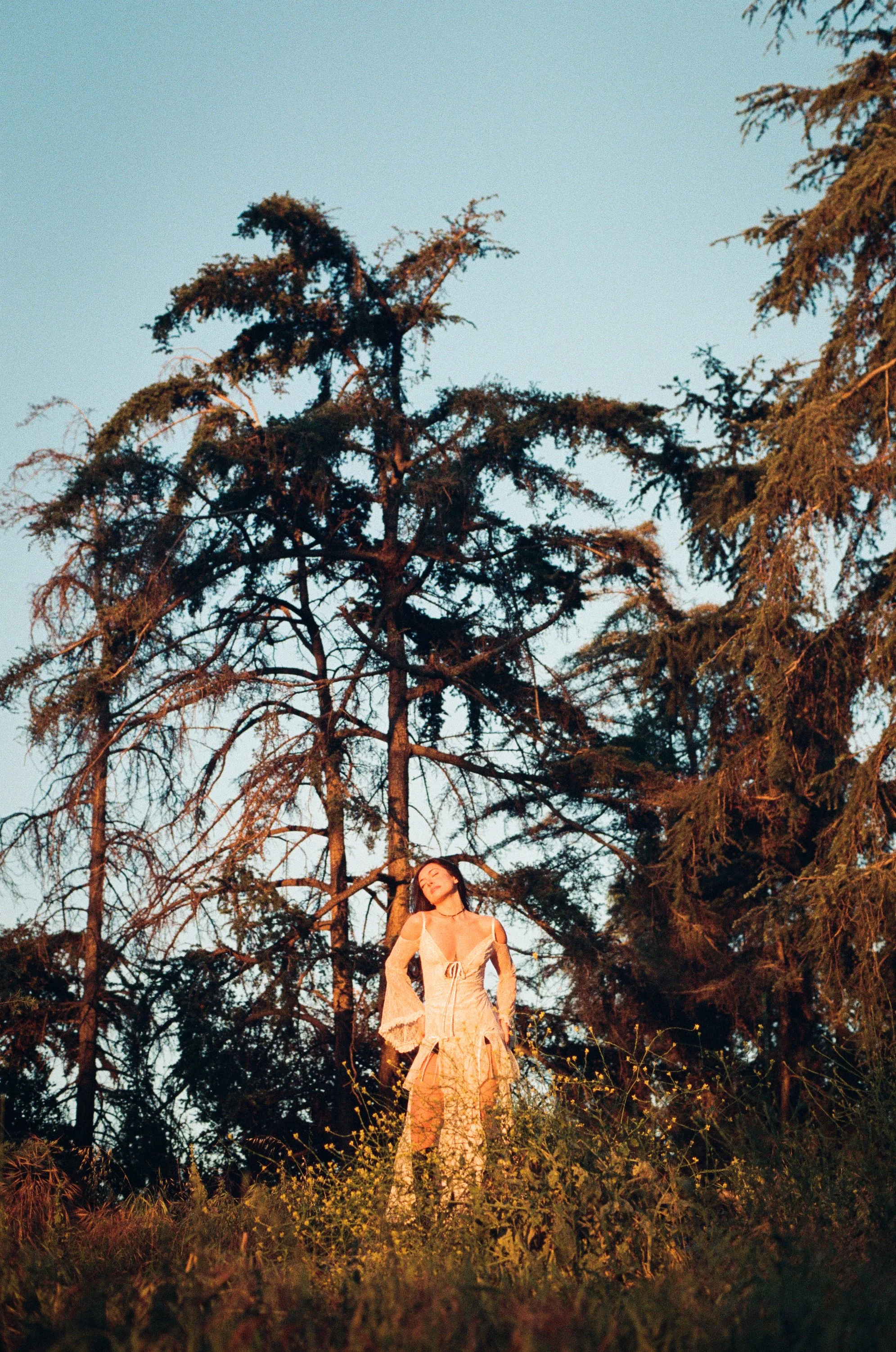 girl in nature wearing white dress and black boots bathed in sunlight