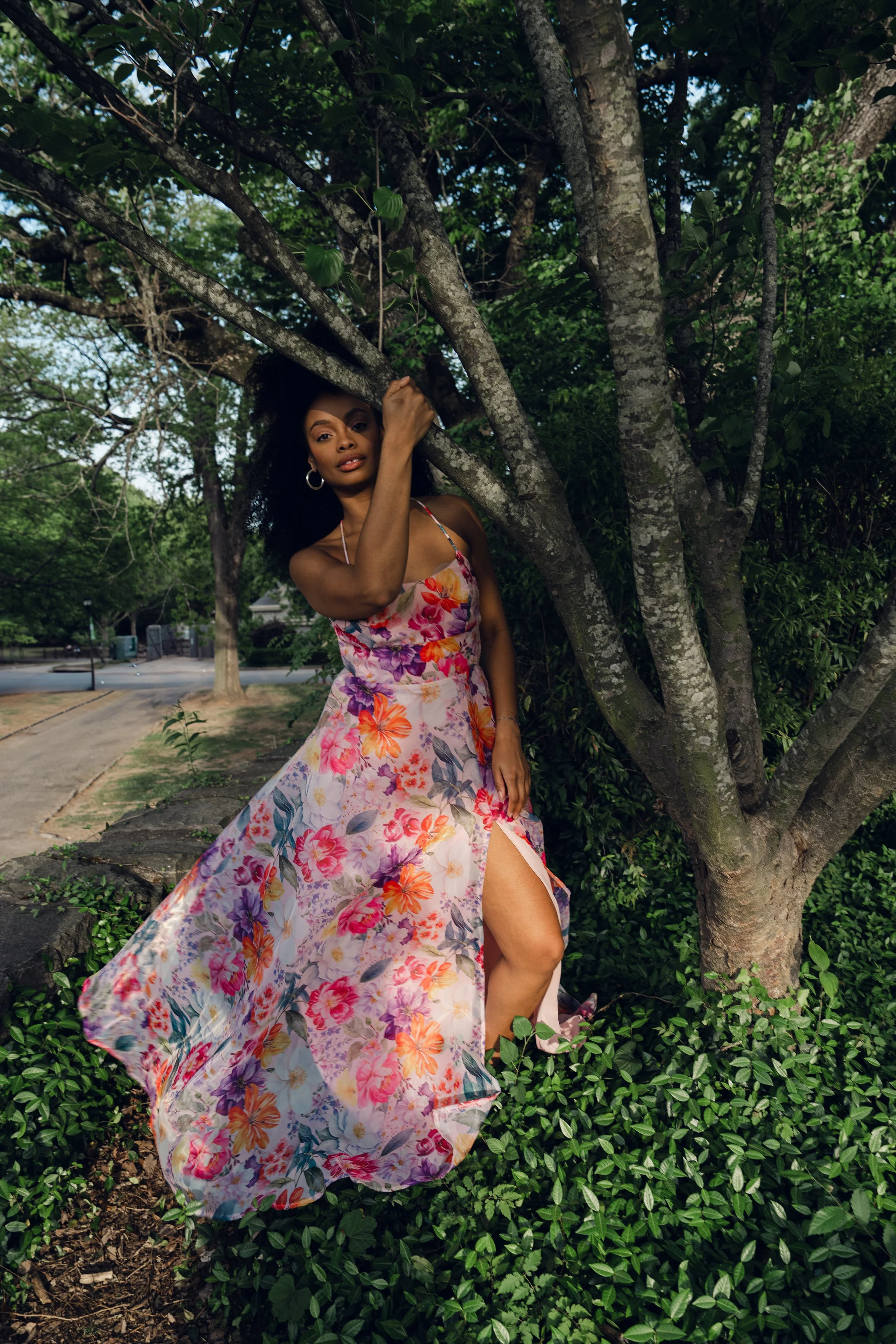 Woman in floral dress stands in the shade of a tree