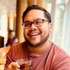 Man with glasses and dark hair smiling