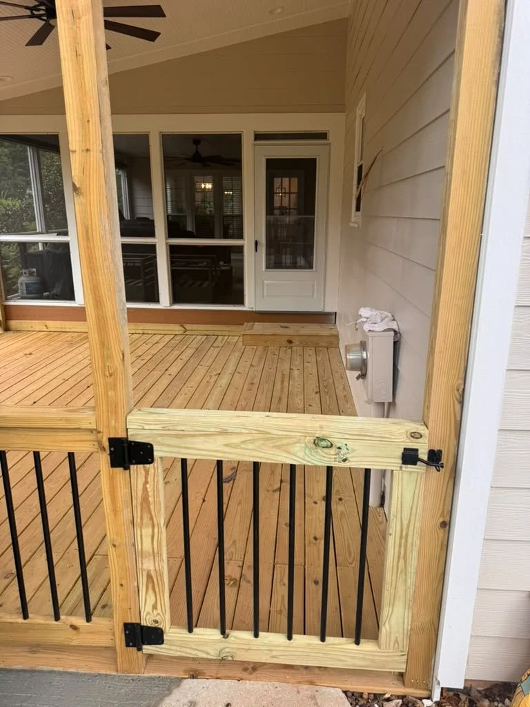 Custom wood deck gate with black metal balusters on a covered porch