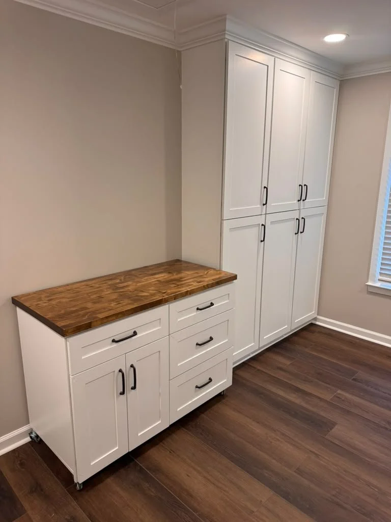 Laundry room folding station with butcher block countertop and tall white cabinets