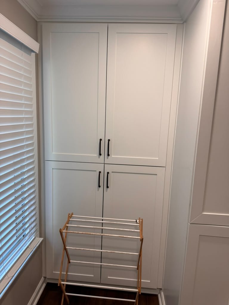 Built-in white shaker linen cabinet in a custom laundry room