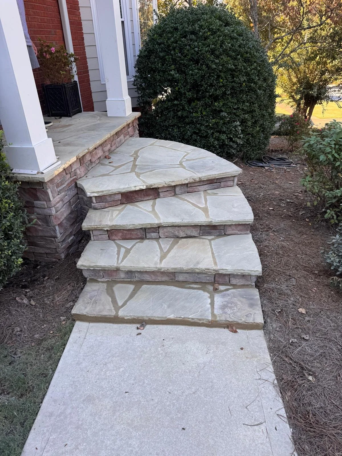 Curved flagstone front steps with stacked stone veneer risers in East Cobb, GA