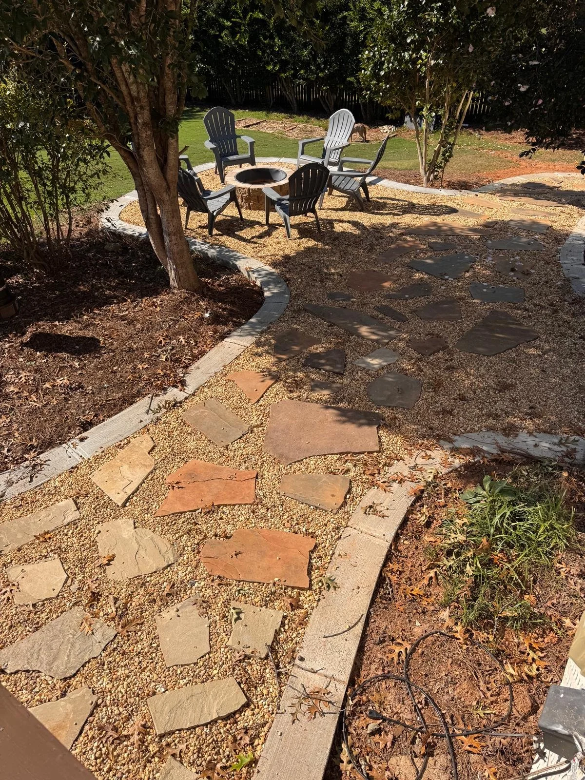 Flagstone stepping stones set in pea gravel leading to a backyard fire pit seating area