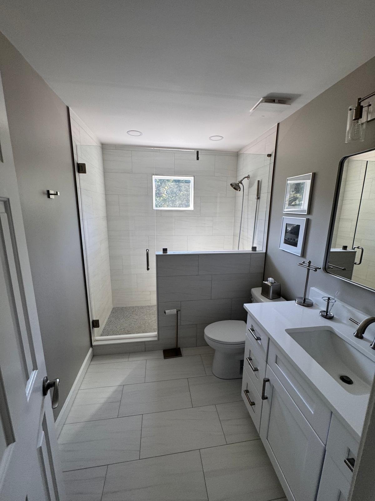Modern bathroom remodel in East Cobb, GA with frameless glass shower, tiled half wall and large-format porcelain floor tile