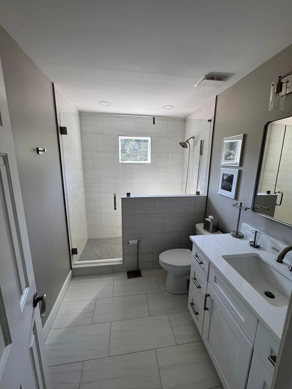 Modern bathroom remodel in East Cobb, GA with frameless glass shower, tiled half wall and large-format porcelain floor tile
