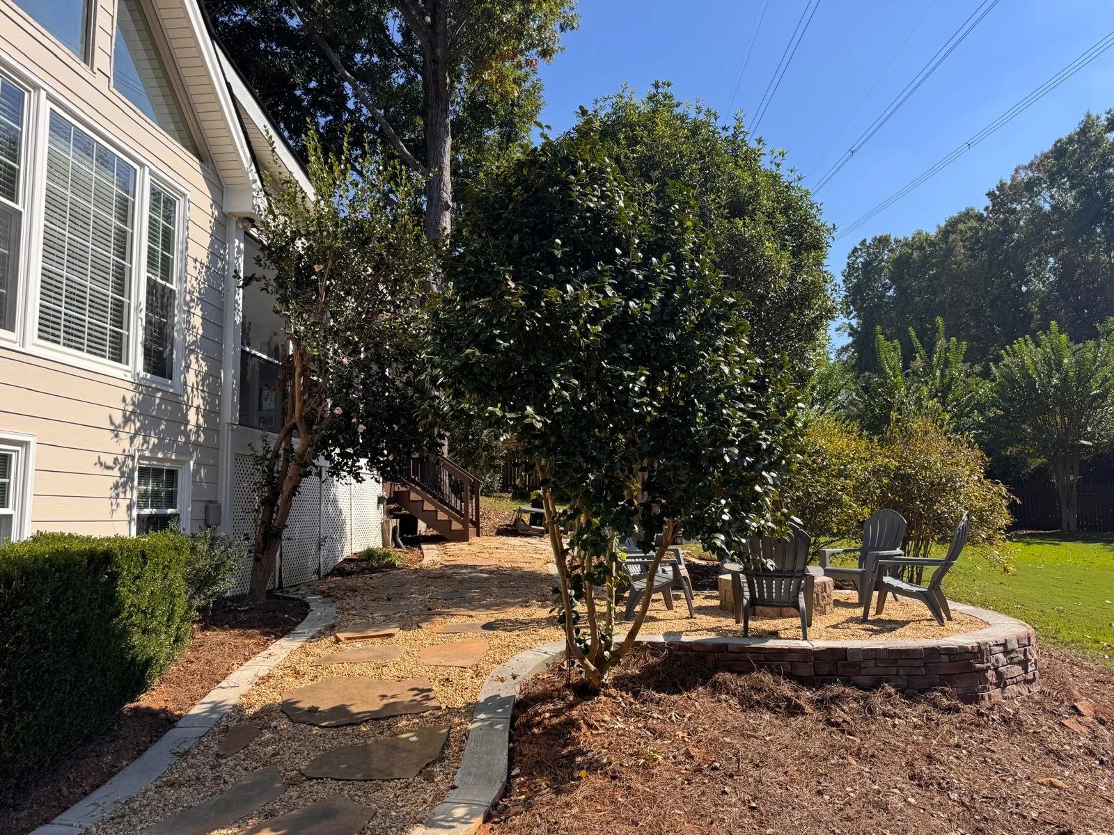 Raised fire pit patio with stacked stone retaining wall and flagstone garden path