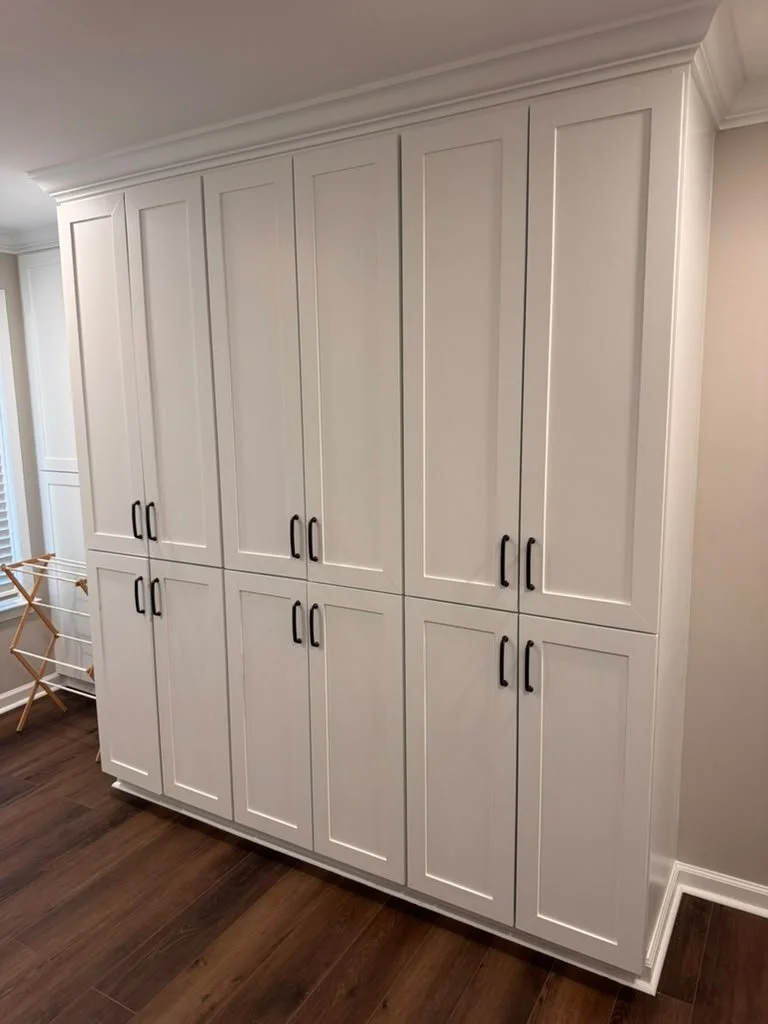 Custom laundry room in East Cobb, GA with floor-to-ceiling white shaker storage cabinets and black pulls