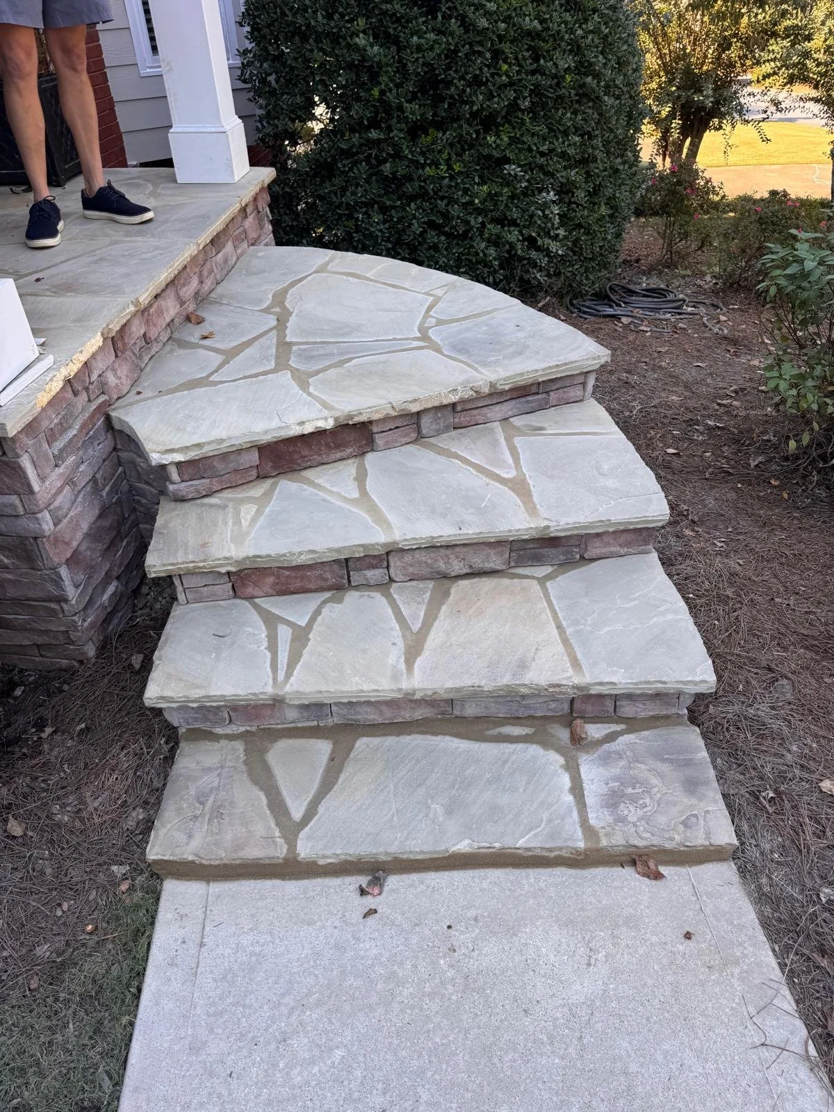 Curved flagstone front steps with stacked stone veneer risers