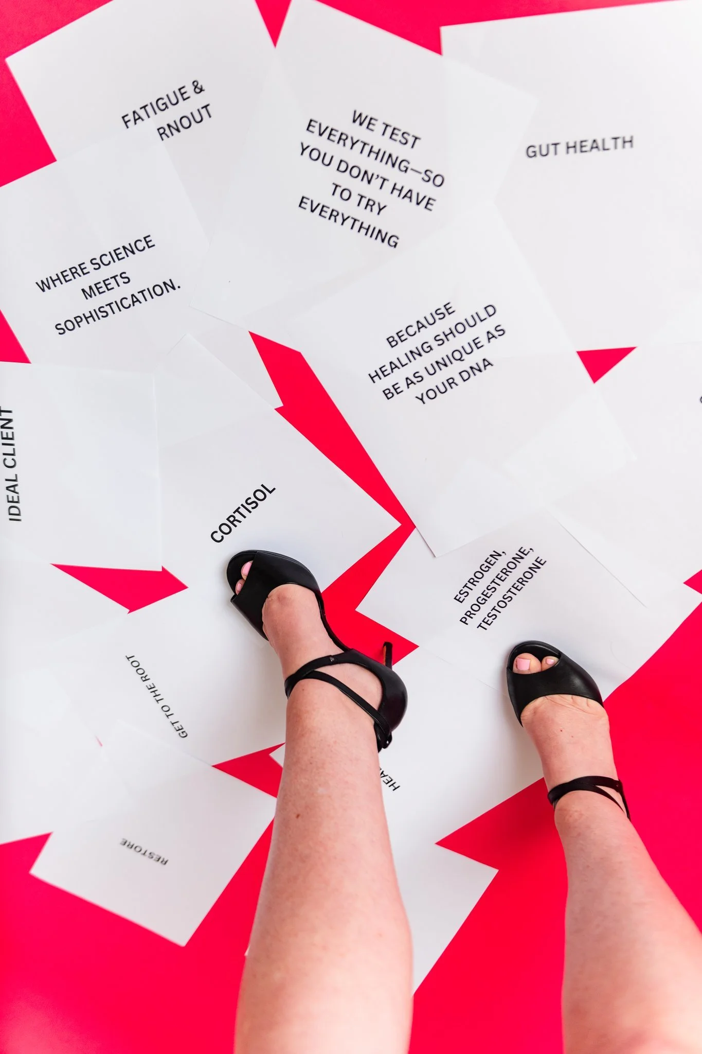 Footwear visible on a person's feet standing on a red floor, with numerous white papers containing health-related messages and scientific terms scattered around.