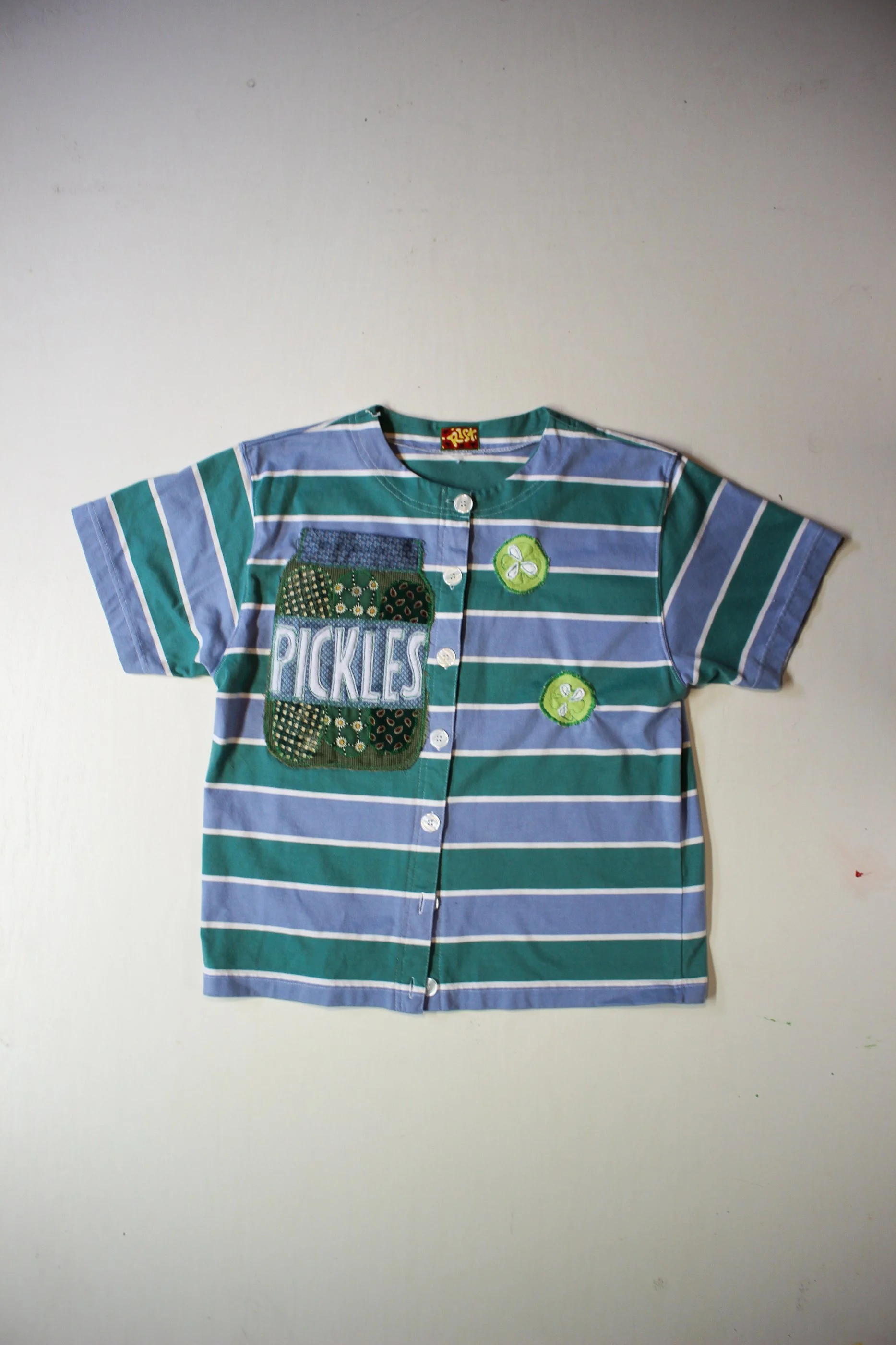 SIZE: Medium best
 PTP: 20” (50.8cm)
BUST: 40” (101.6cm)
LENGTH: 22” (55.88cm)

MATERIAL: Most likely cotton shirt. Appliques are other.

ETC: Features a pickle jar pocket. Front buttons.