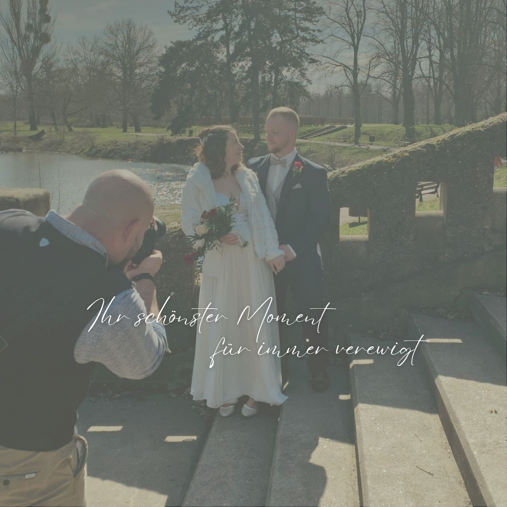 Ein Paar bei einer Hochzeitsfotografie im Freien an einem sonnigen Tag, mit einem Fotografen, das sie fotografiert. Im Hintergrund sind Bäume, Wasser und eine grüne Wiese sichtbar. Es ist ein romantischer Moment, der durch den Text 'Ihr schönster Moment für immer verewigt' auf dem Bild betont wird.