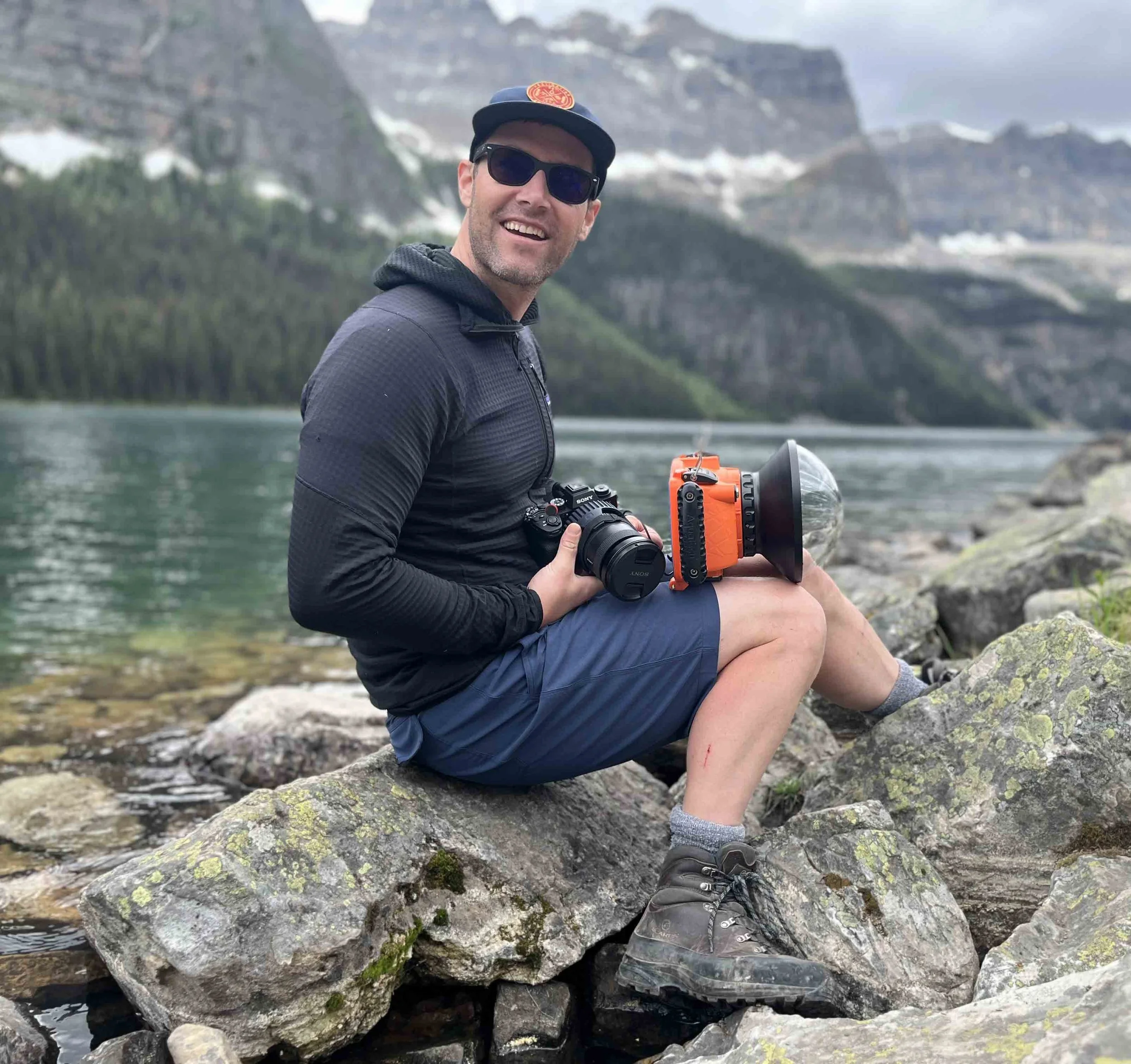 A photographer in front of a mountain lake.