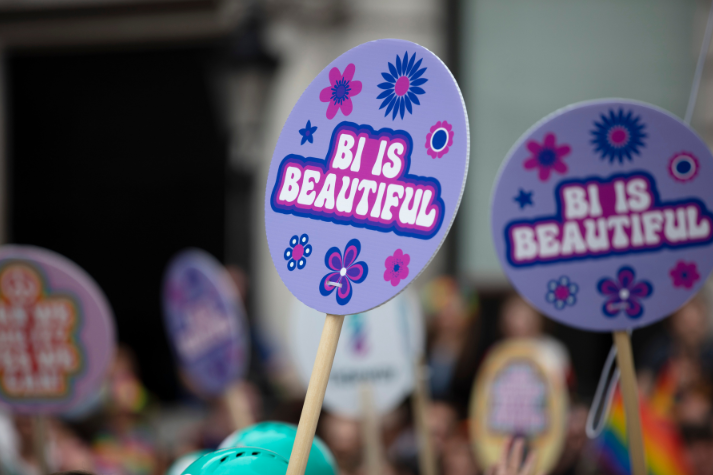 Someone in Minneapolis who is coming out as bi holding a sign that reads "Bi is Beautiful"