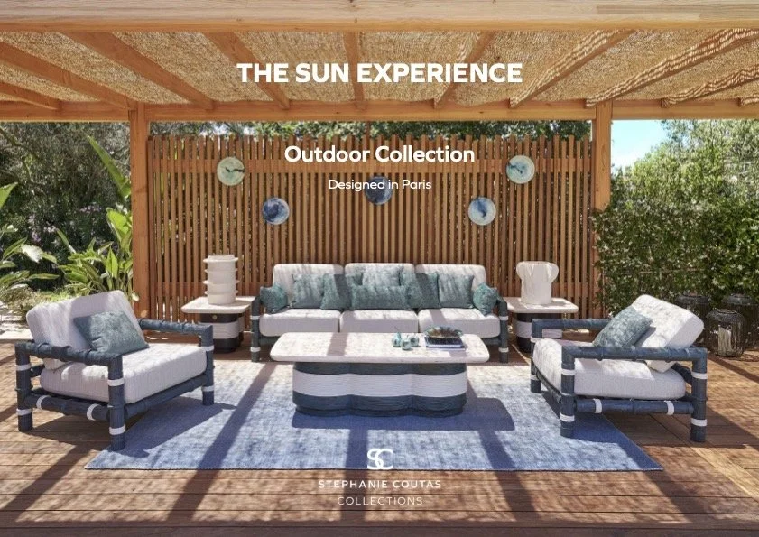 Outdoor patio furniture set with a sofa, two chairs, and a coffee table under a covered pergola with green foliage in the background and decorative plates on a wooden slat wall.