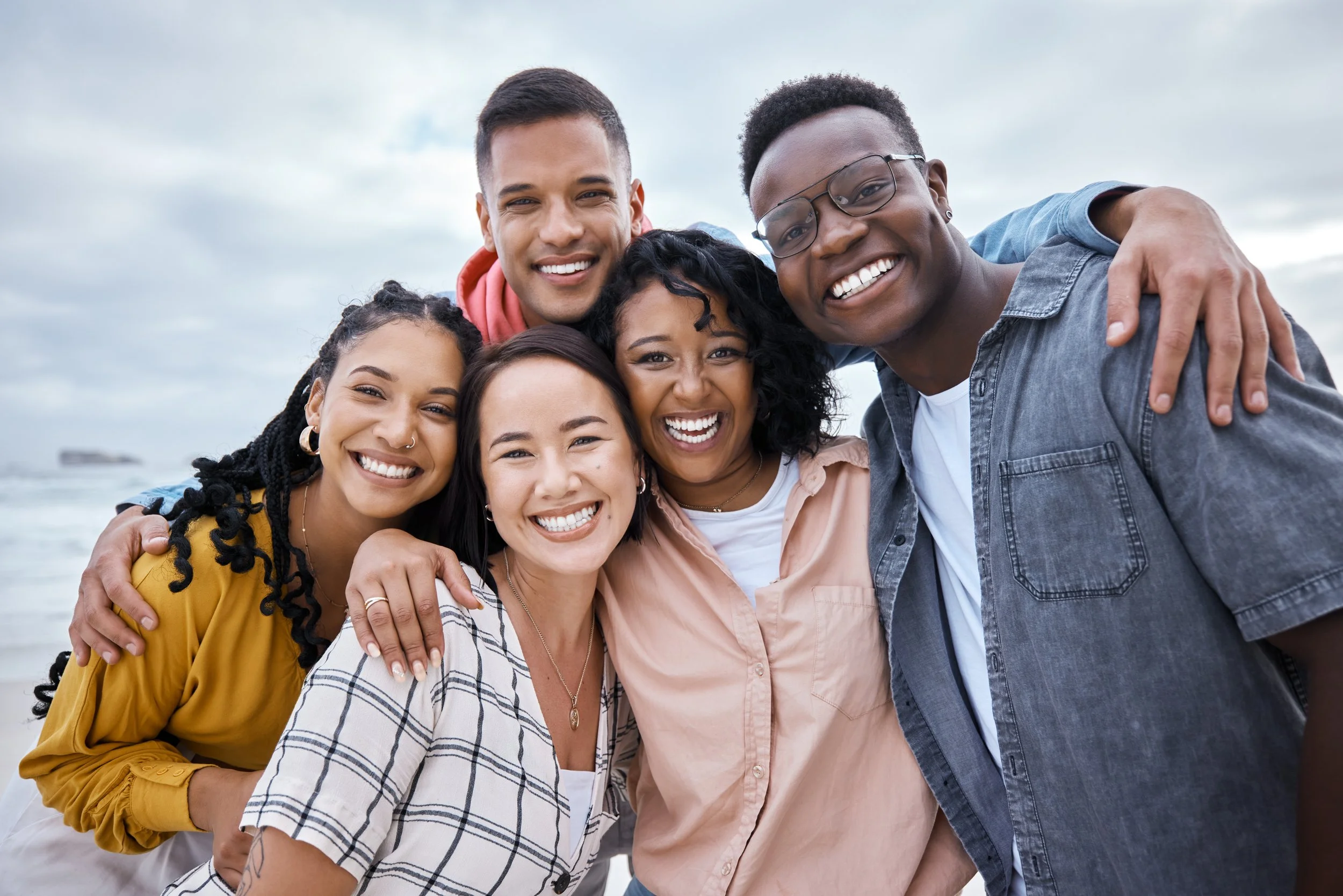 Friends, diversity and portrait at beach, ocean and outdoor nature for fun, happiness and travel. Group of happy young people at sea for holiday, vacation and smile for relaxing weekend trip together