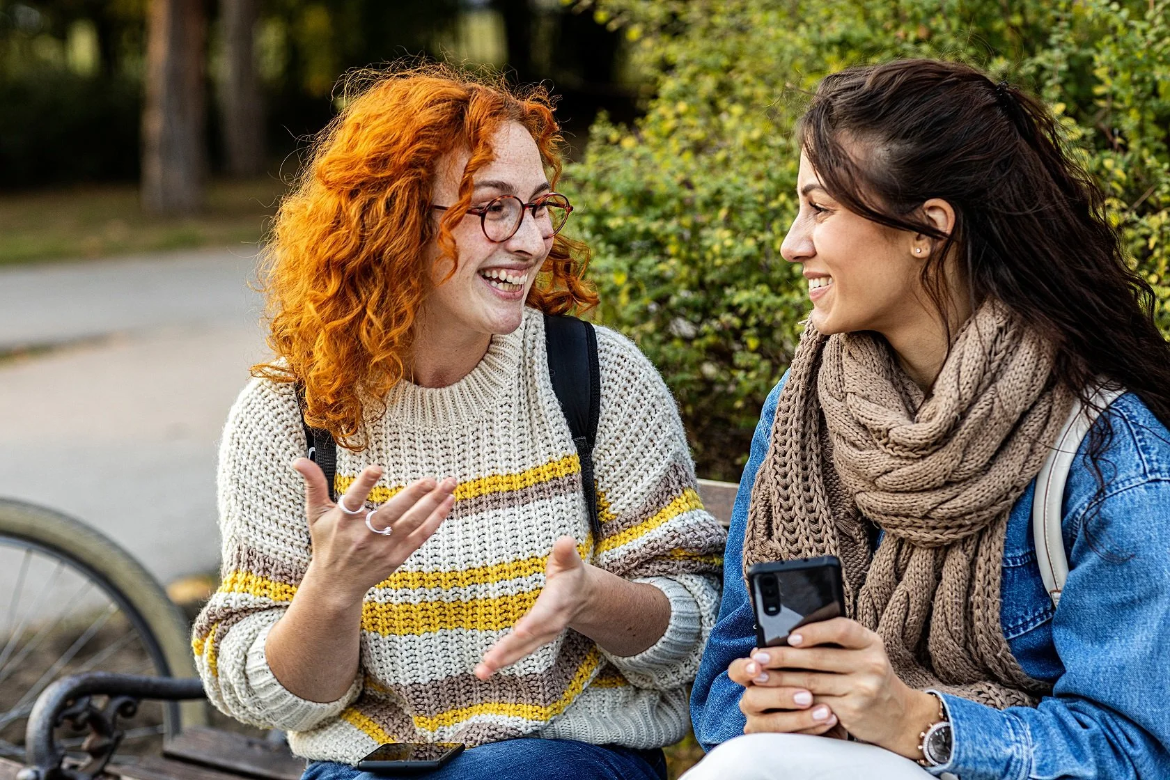 Two women sitting on a park bench having a conversation