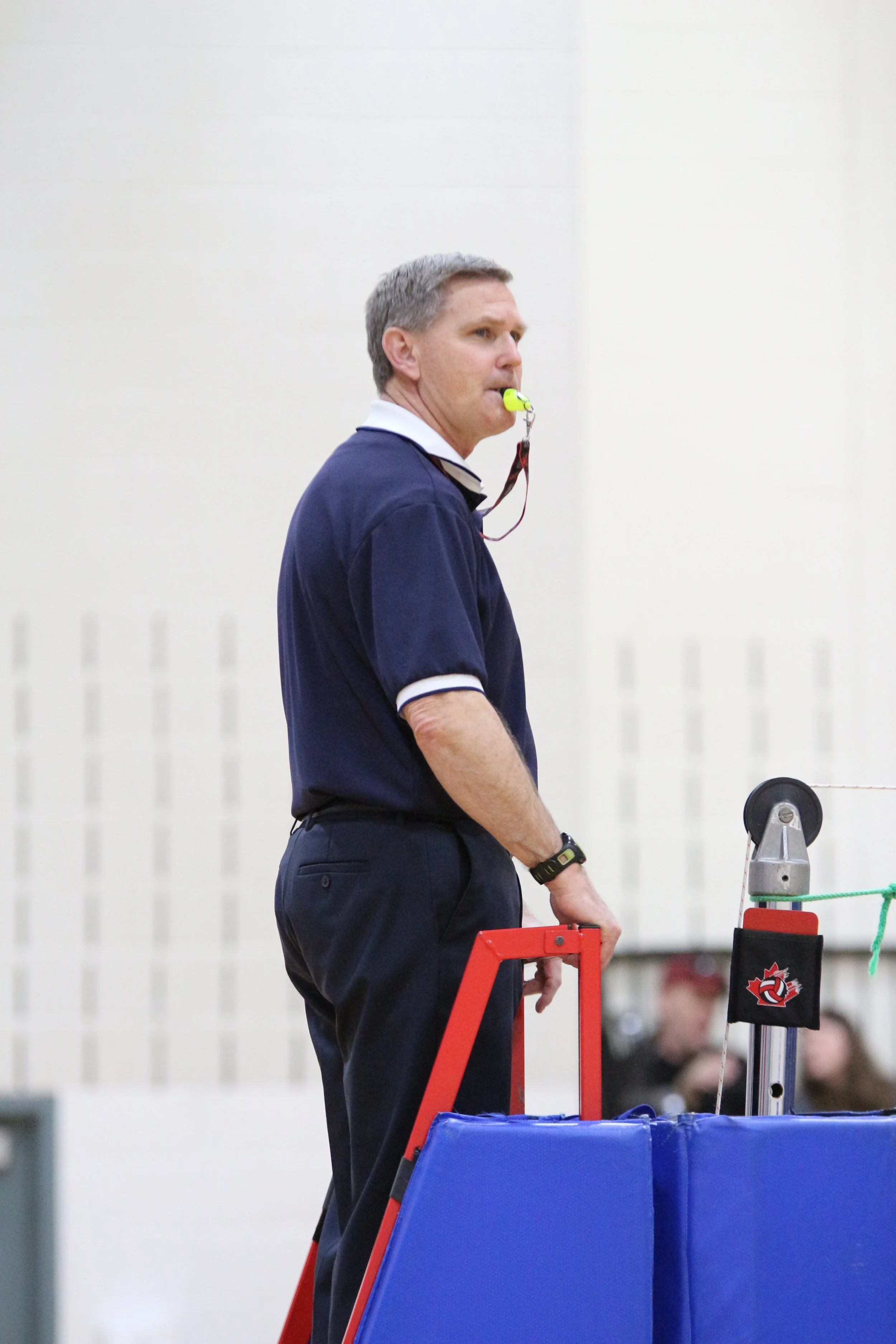 Dean with whistle in his mouth refereeing volleyball match