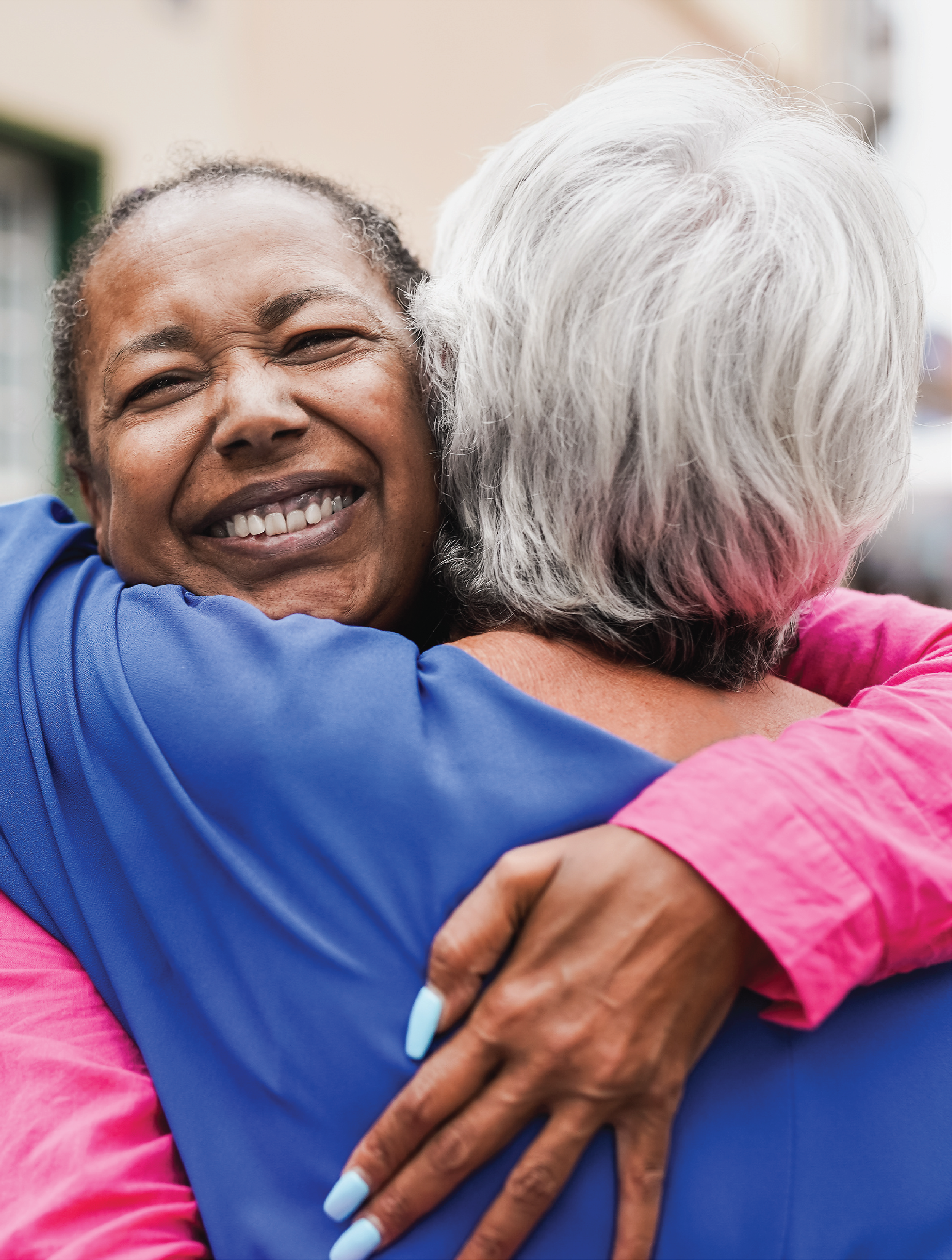 Senior multiracial female friends meeting and hugging each other in the city